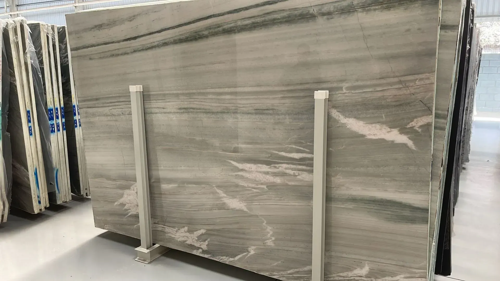Large gray marble slab standing upright on a warehouse pallet with support braces