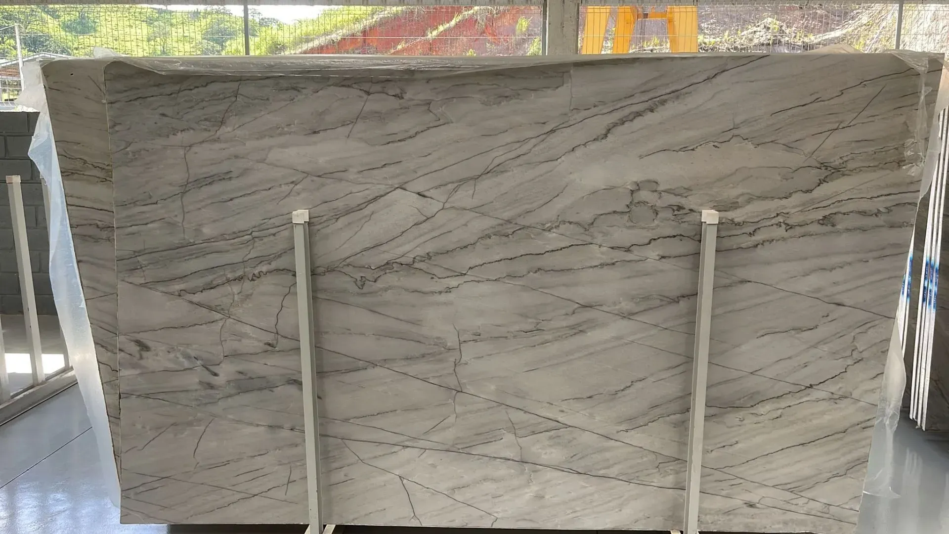 Large gray-and-white marble slab displayed upright on a stand indoors