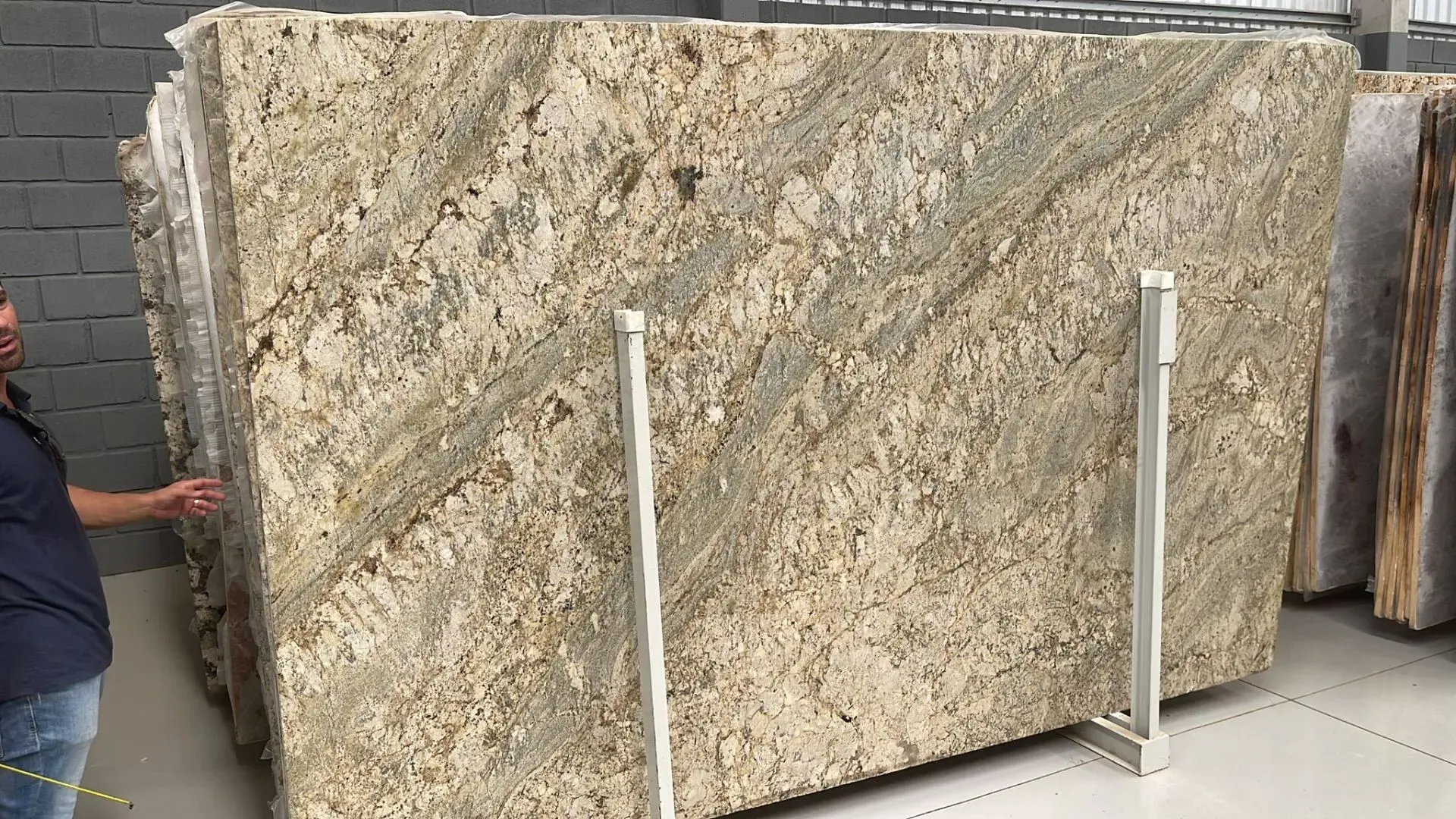 Large granite slab standing on display in a warehouse, with a person partially visible at left.