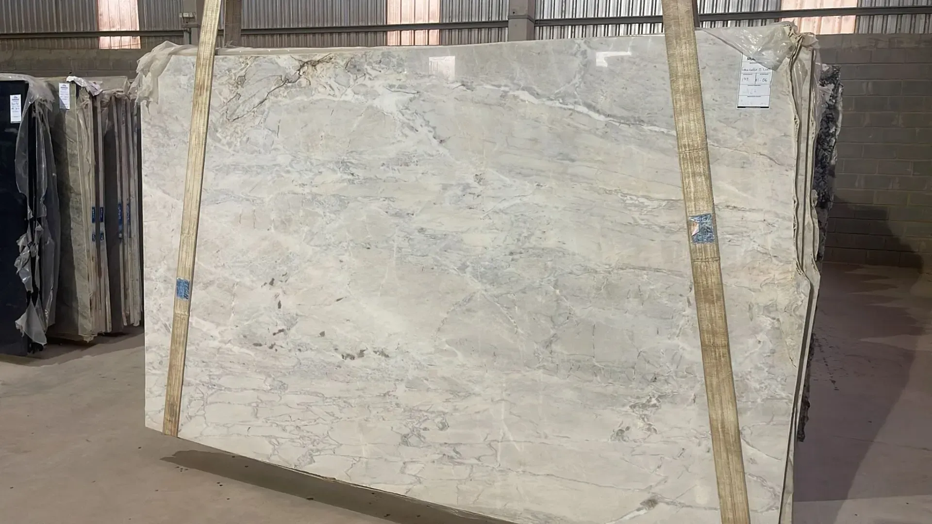 Large pale stone slab secured with straps in a warehouse or stone yard