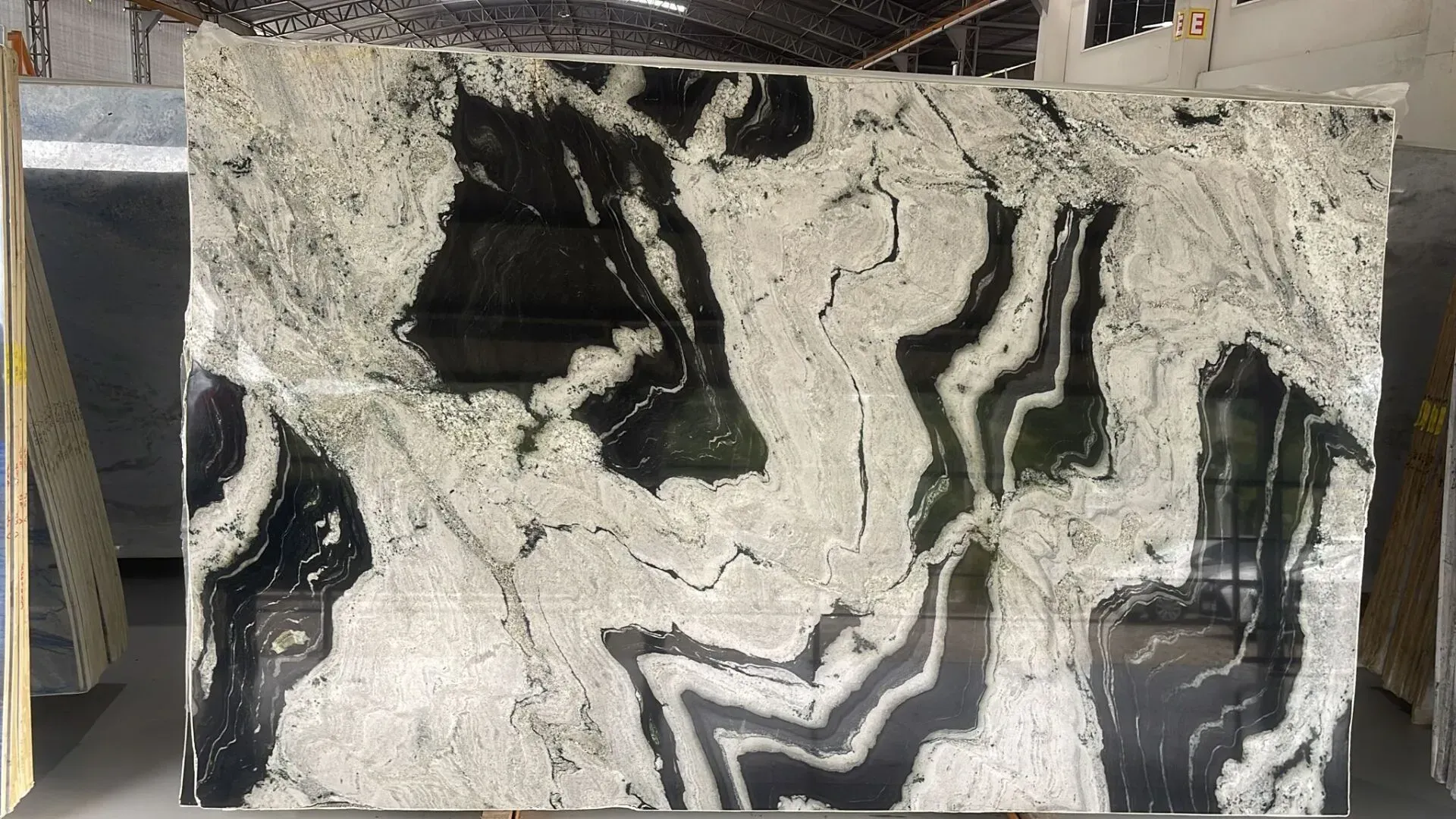 Black-and-white marbled stone slab with bold wavy veins in a workshop setting