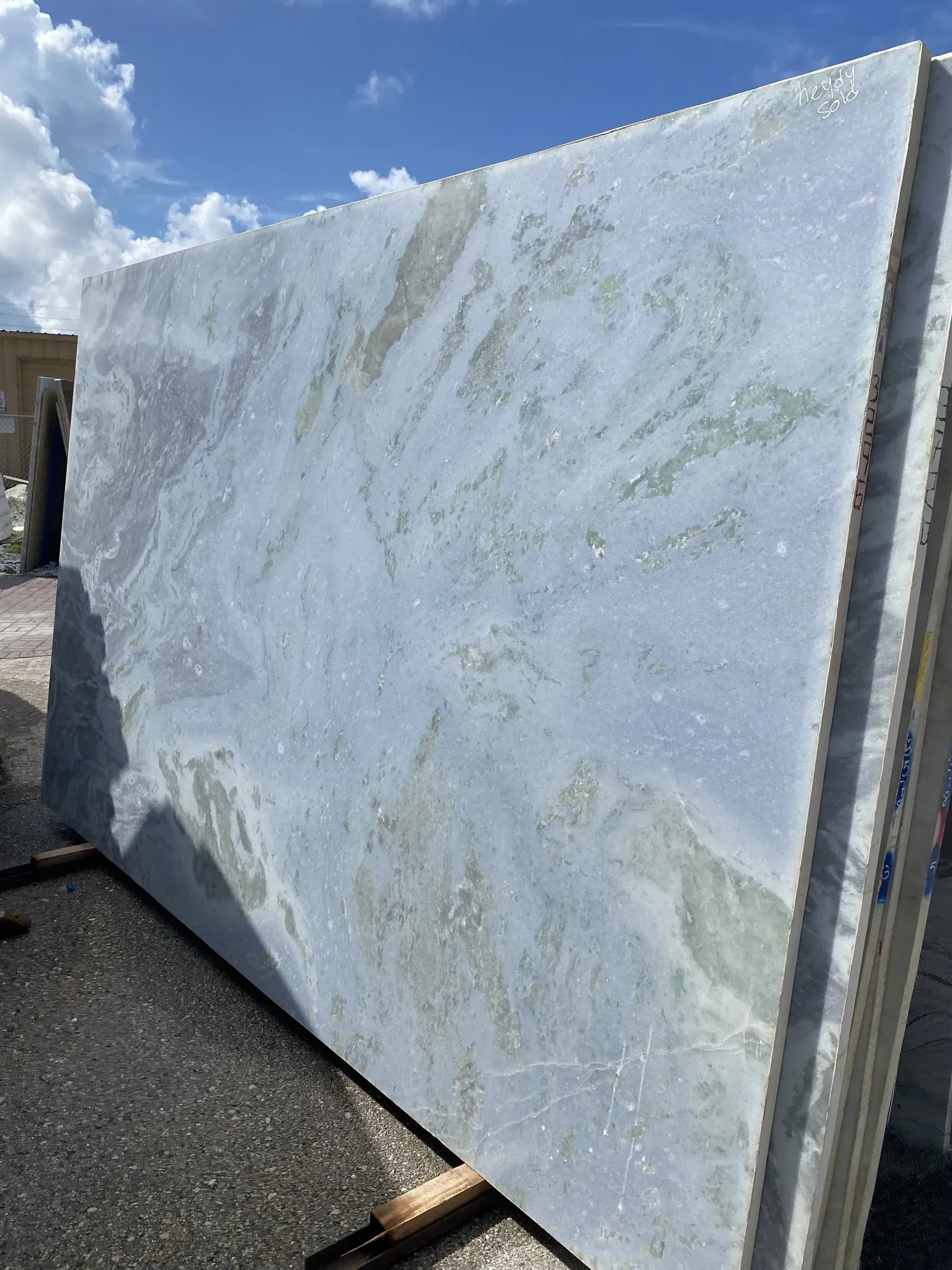 Large white marble slab standing outdoors on pavement under a cloudy sky