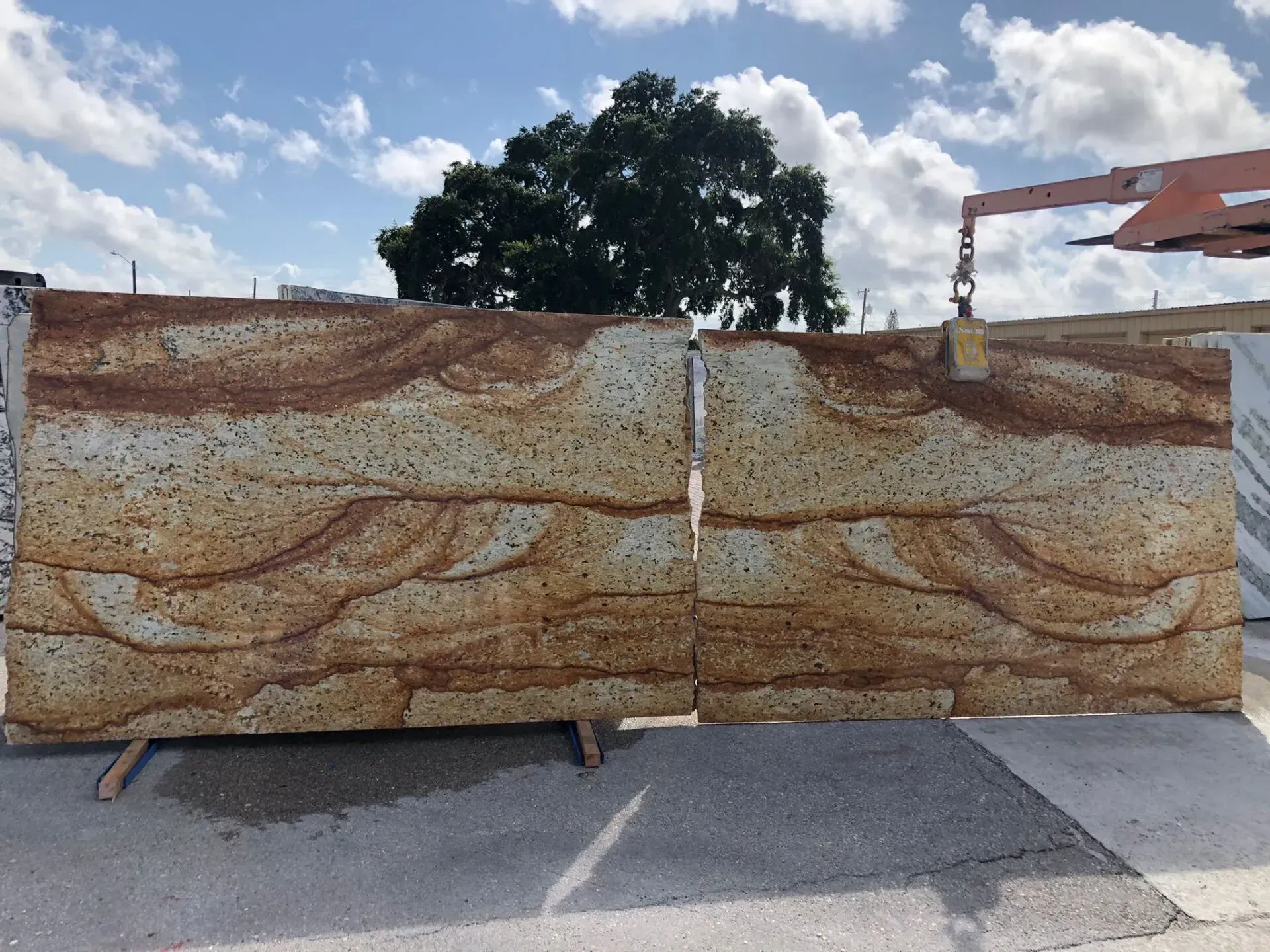Two large rust-streaked metal slabs standing outdoors on a concrete surface under a blue sky