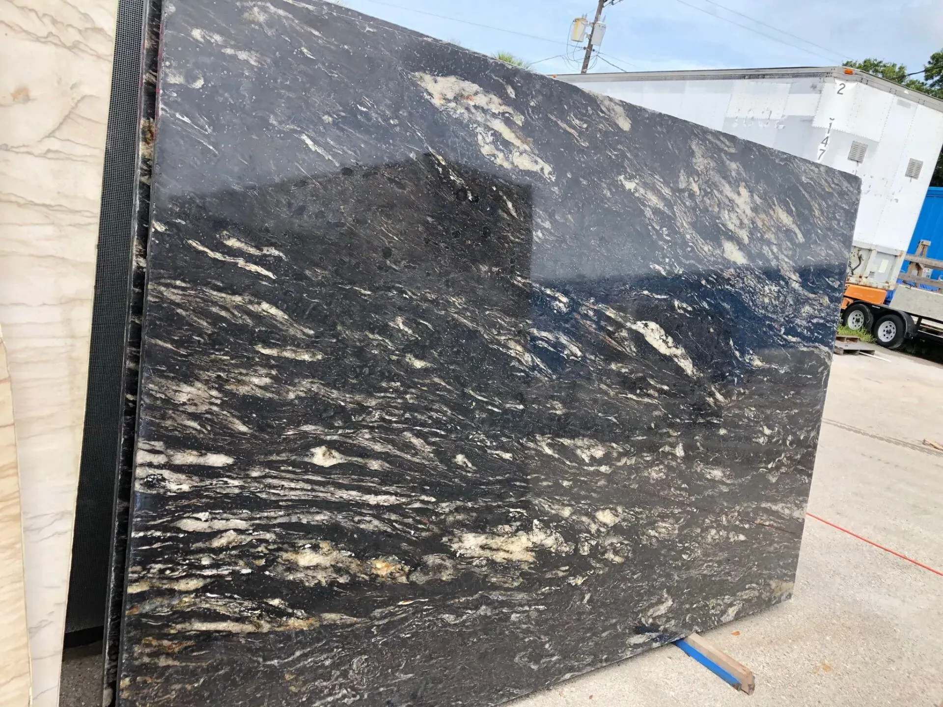 Large black stone slab with white veining, standing outdoors on a worksite.
