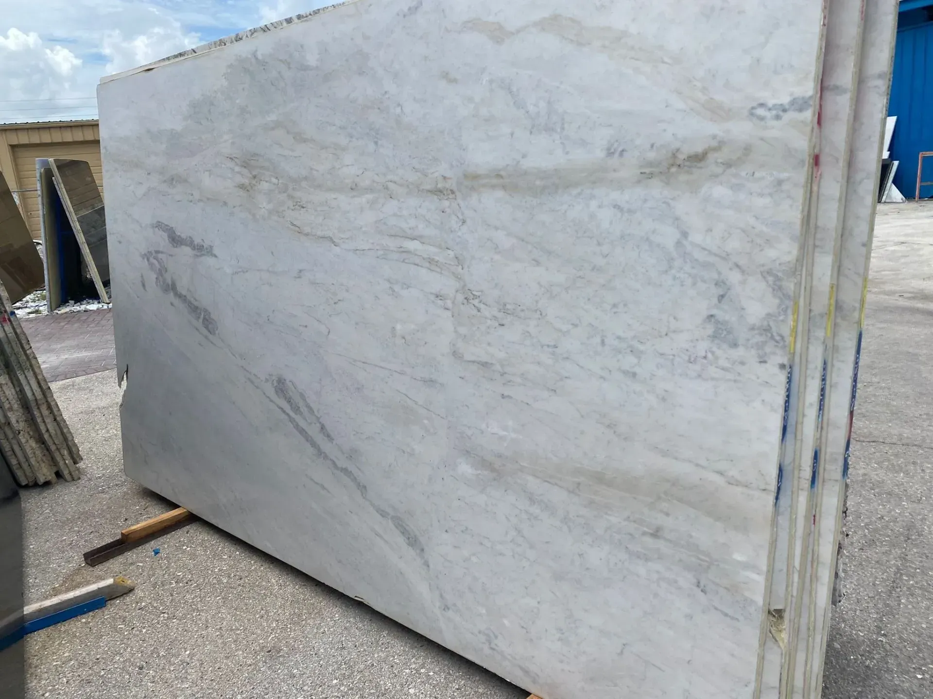 Large white marble slab leaning outdoors in a storage yard
