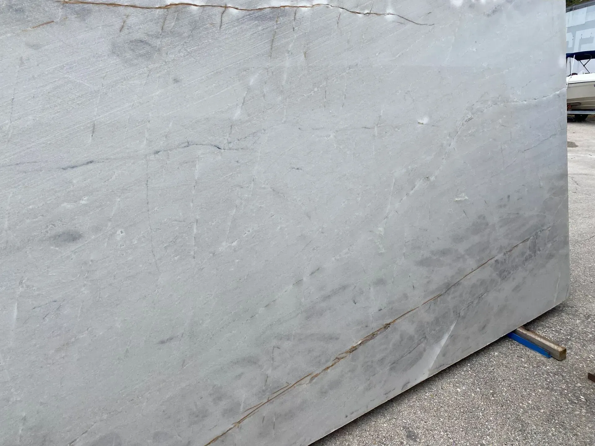 Large gray concrete slab leaning against a wall, with a blue support at the bottom right.