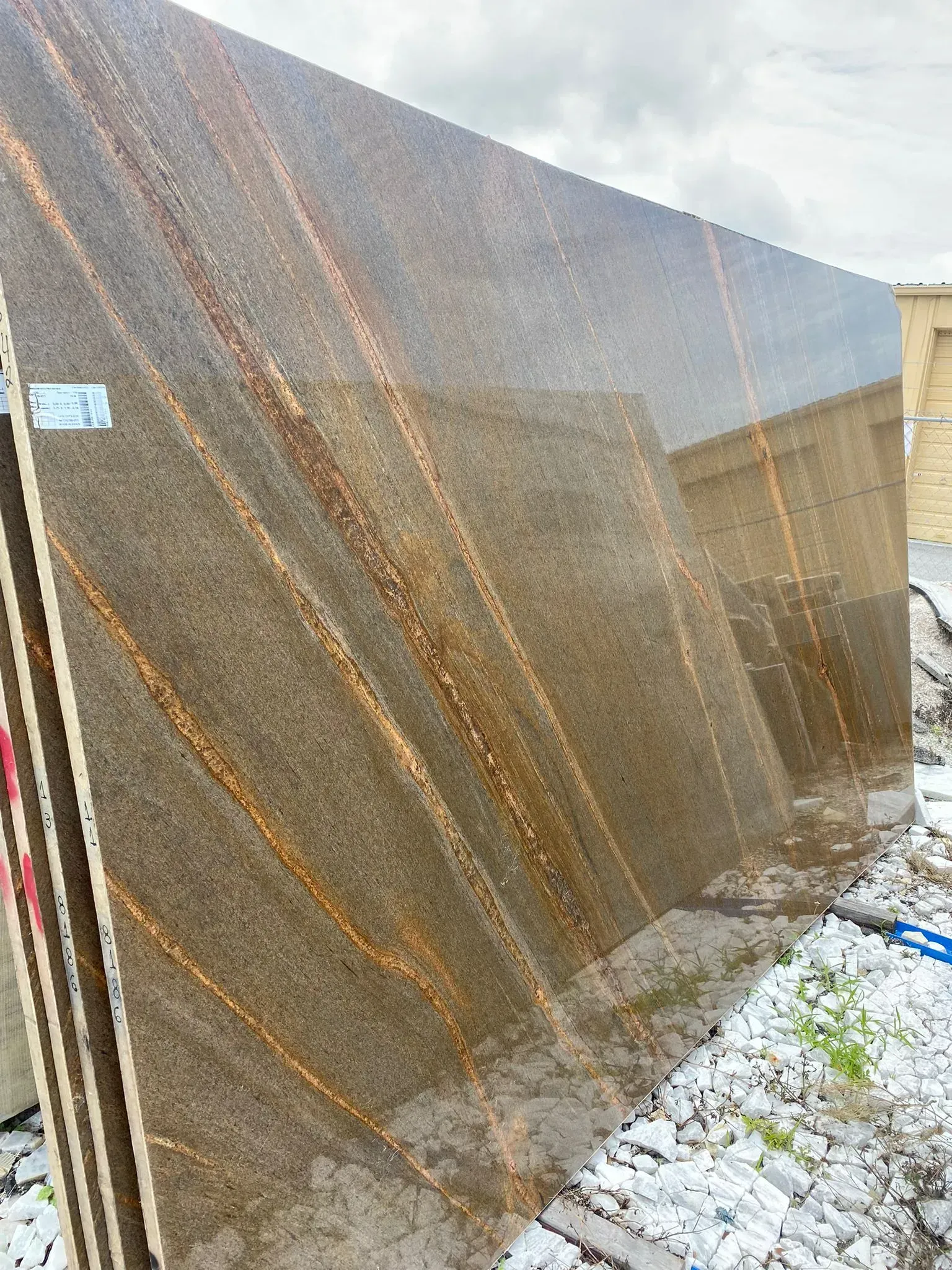 Large brown metal panel leaning outdoors on snowy ground beside a building.