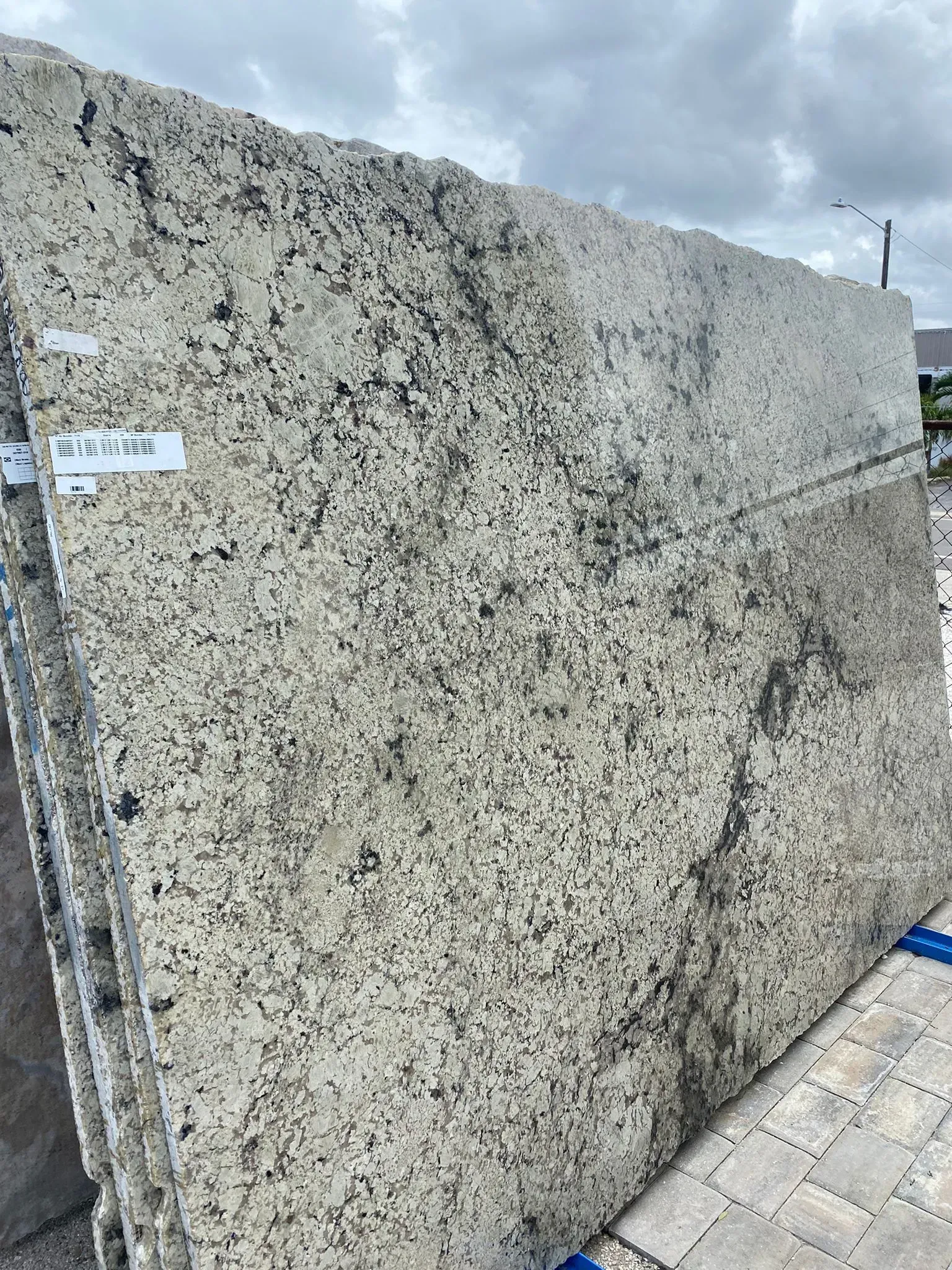 Large speckled granite slab standing outdoors on a paved surface.