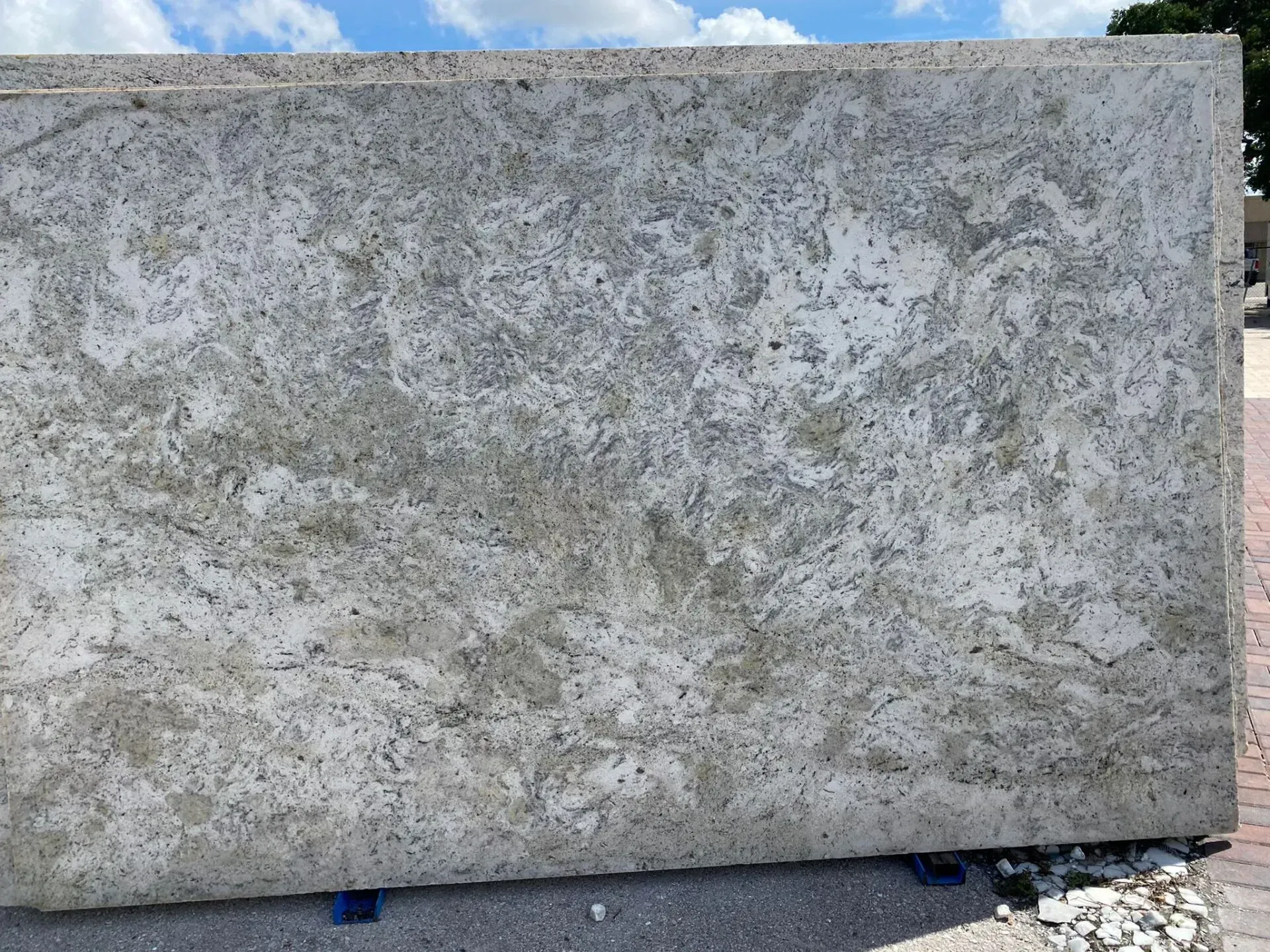 Large gray stone slab leaning outdoors against a blue-sky backdrop