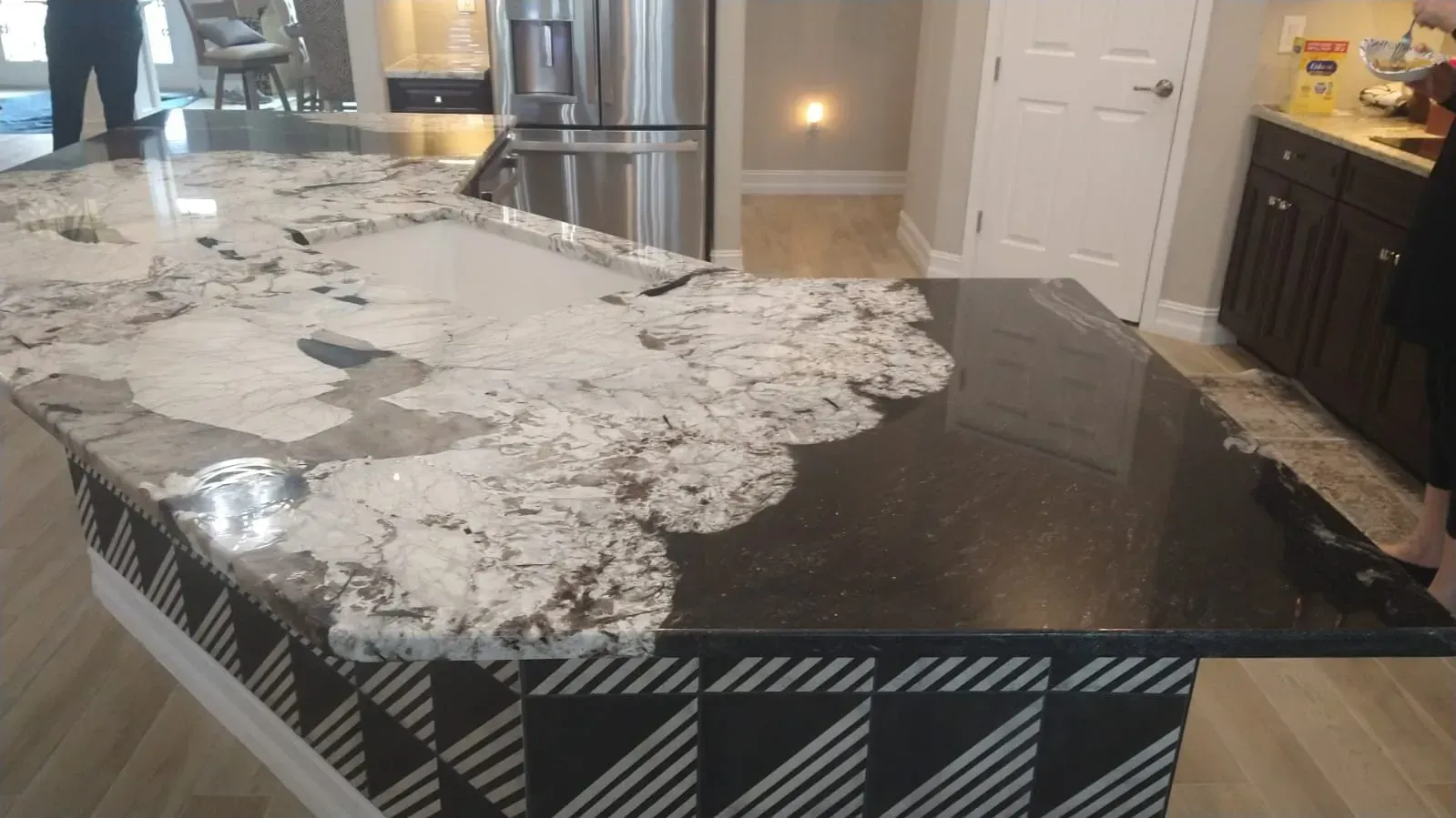 Modern kitchen island with dark countertop covered by a white patterned runner and decorative items