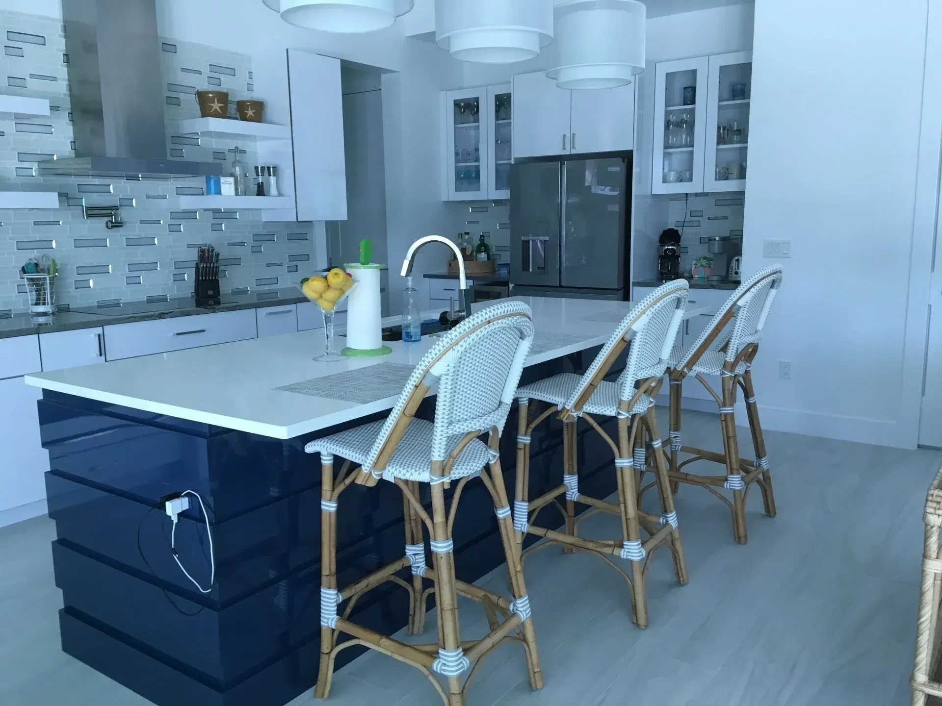 Modern white kitchen with a dark island and wicker bar stools