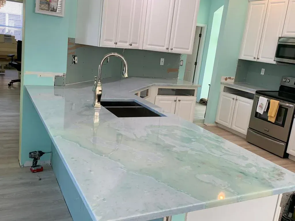 Bright kitchen with mint-green island, white cabinets, and stainless steel appliances.