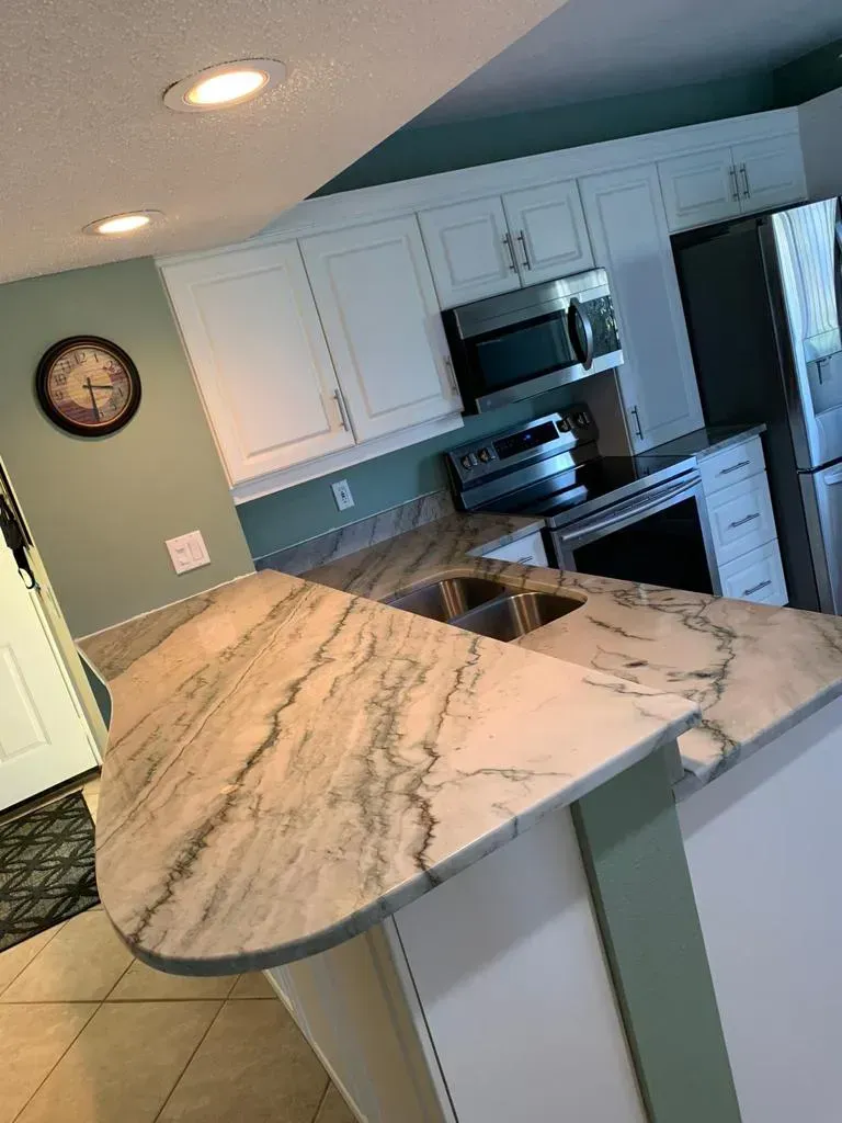 Modern kitchen with marble island, white cabinets, tiled floor, and stainless steel appliances.