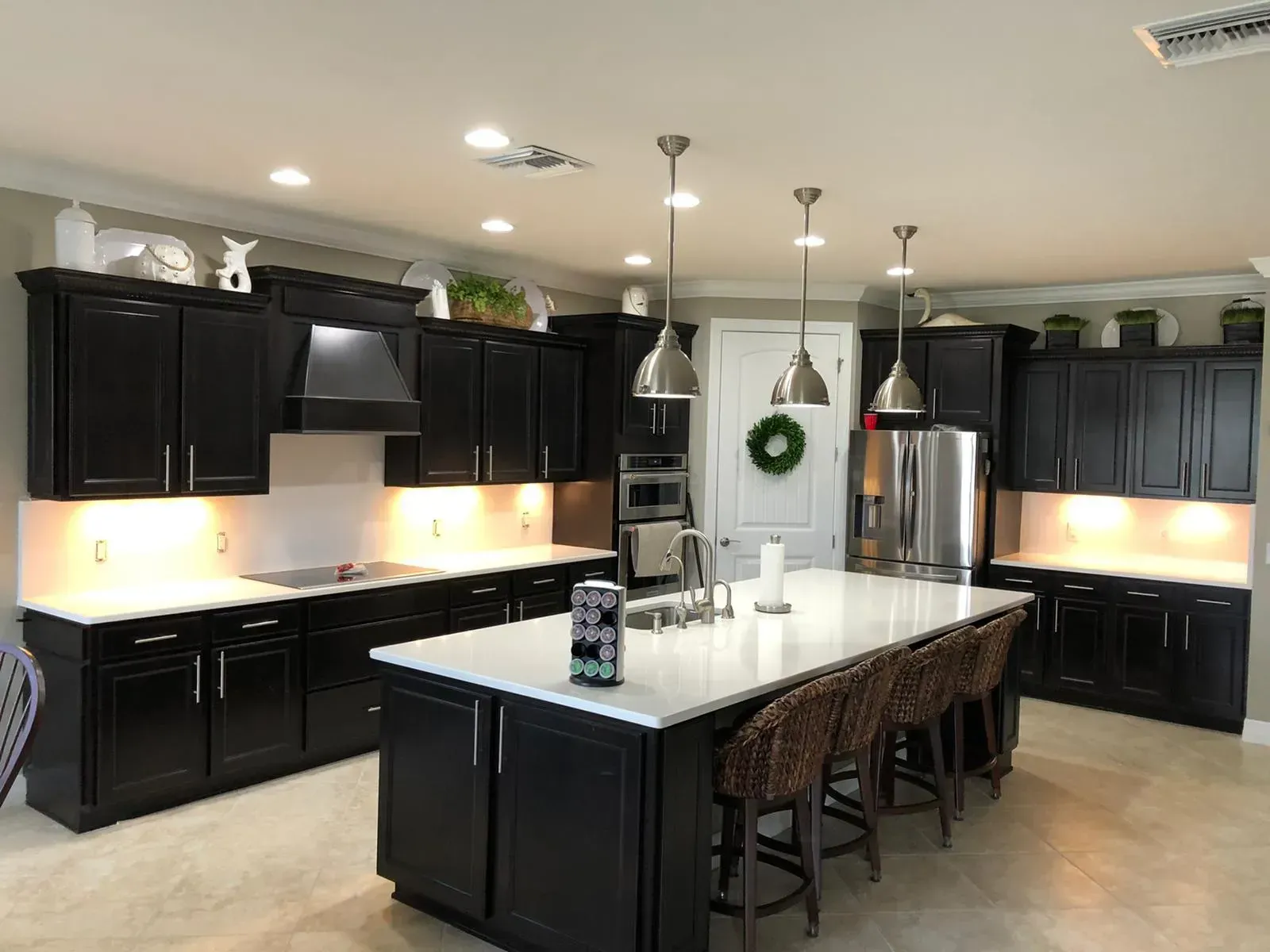 Modern kitchen with black cabinets, white island, pendant lights, and stainless steel appliances