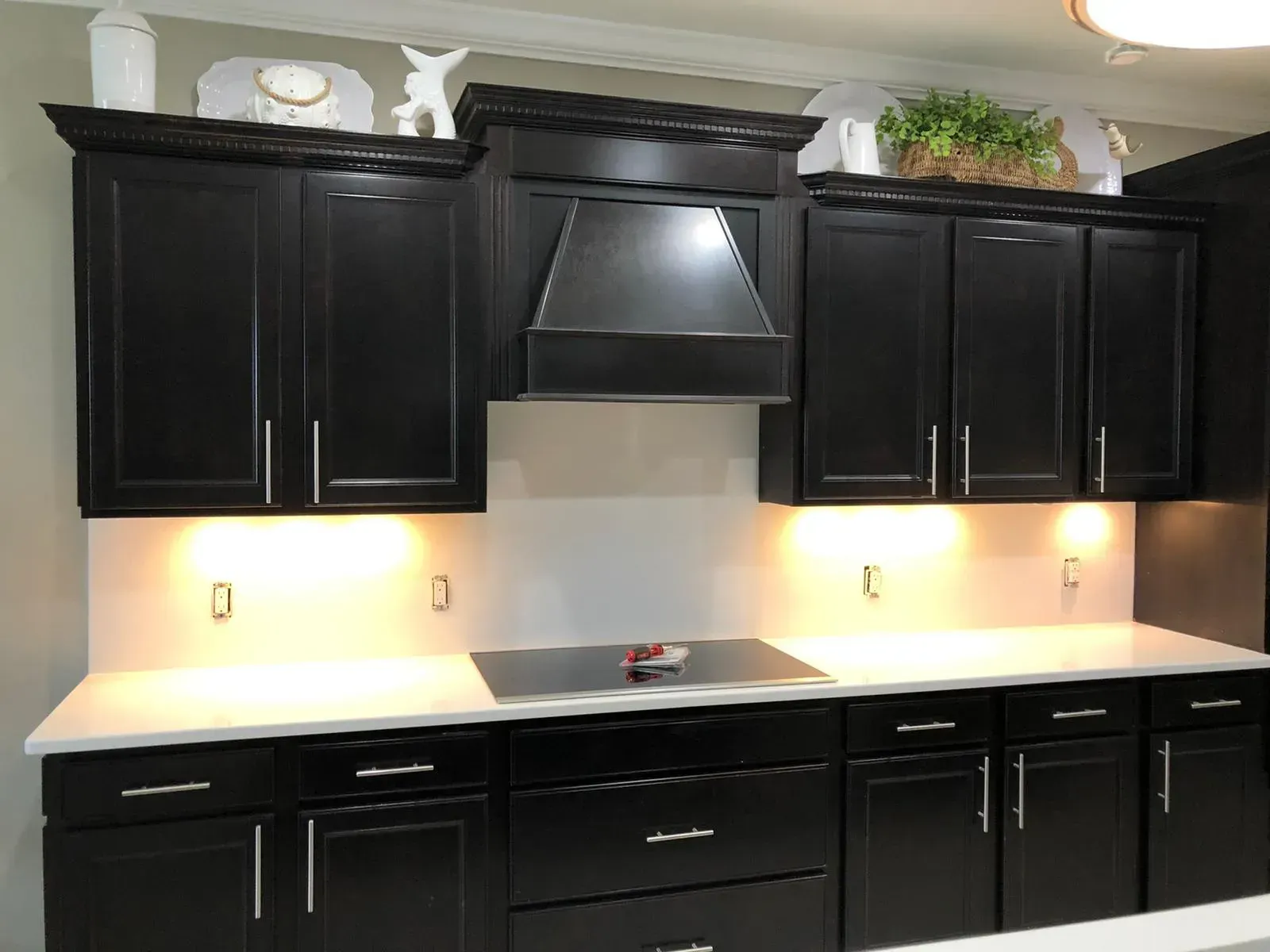 Modern kitchen with black cabinets, white countertops, and under-cabinet lighting
