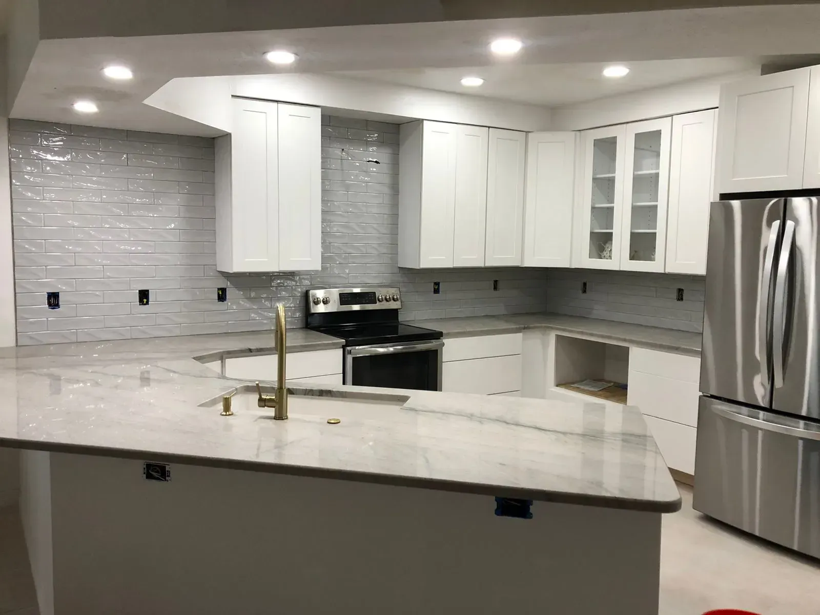 Modern white kitchen with island, stainless steel appliances, and marble-look countertops