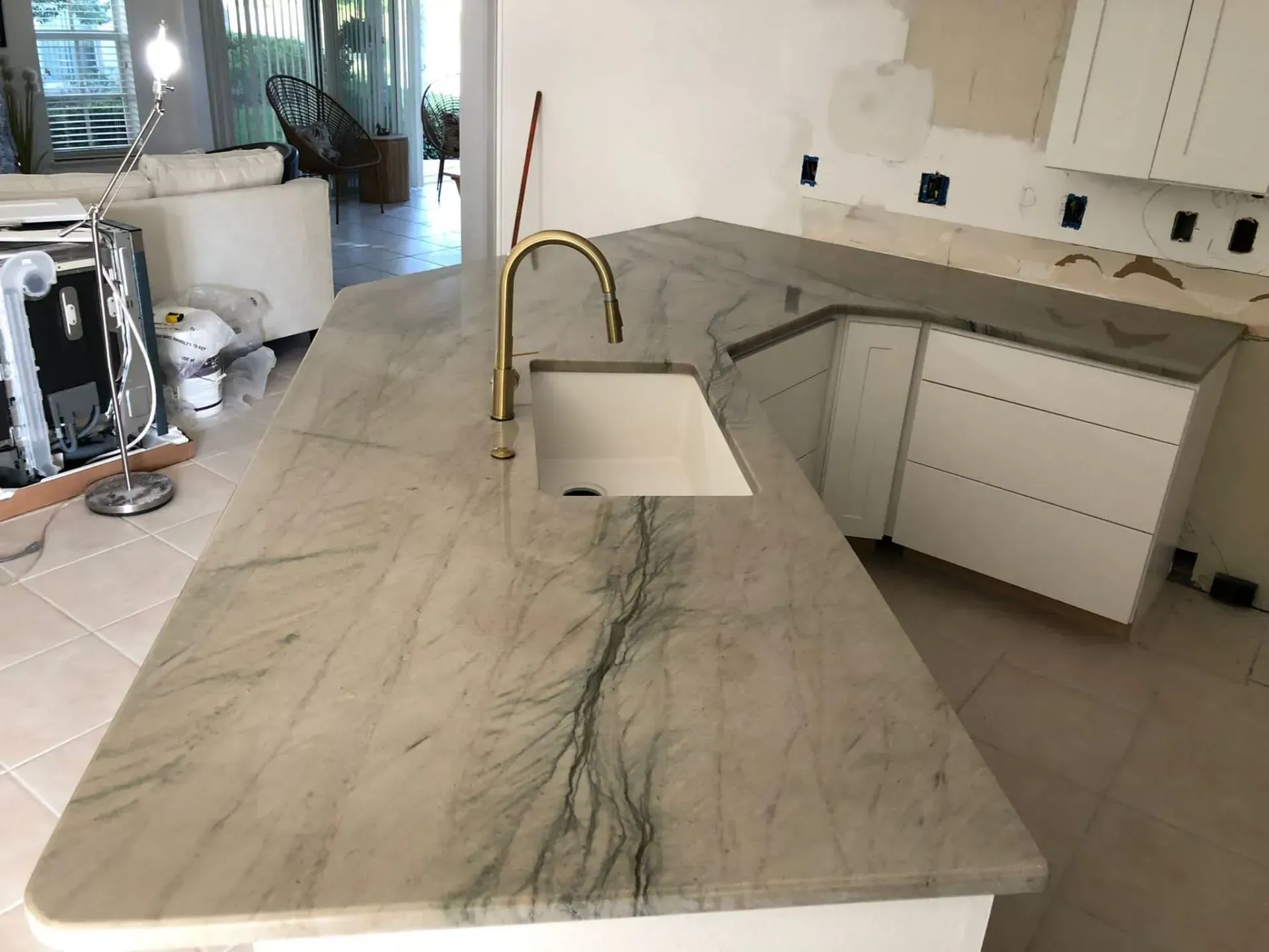 Modern kitchen with marble island, brass faucet, and white cabinetry
