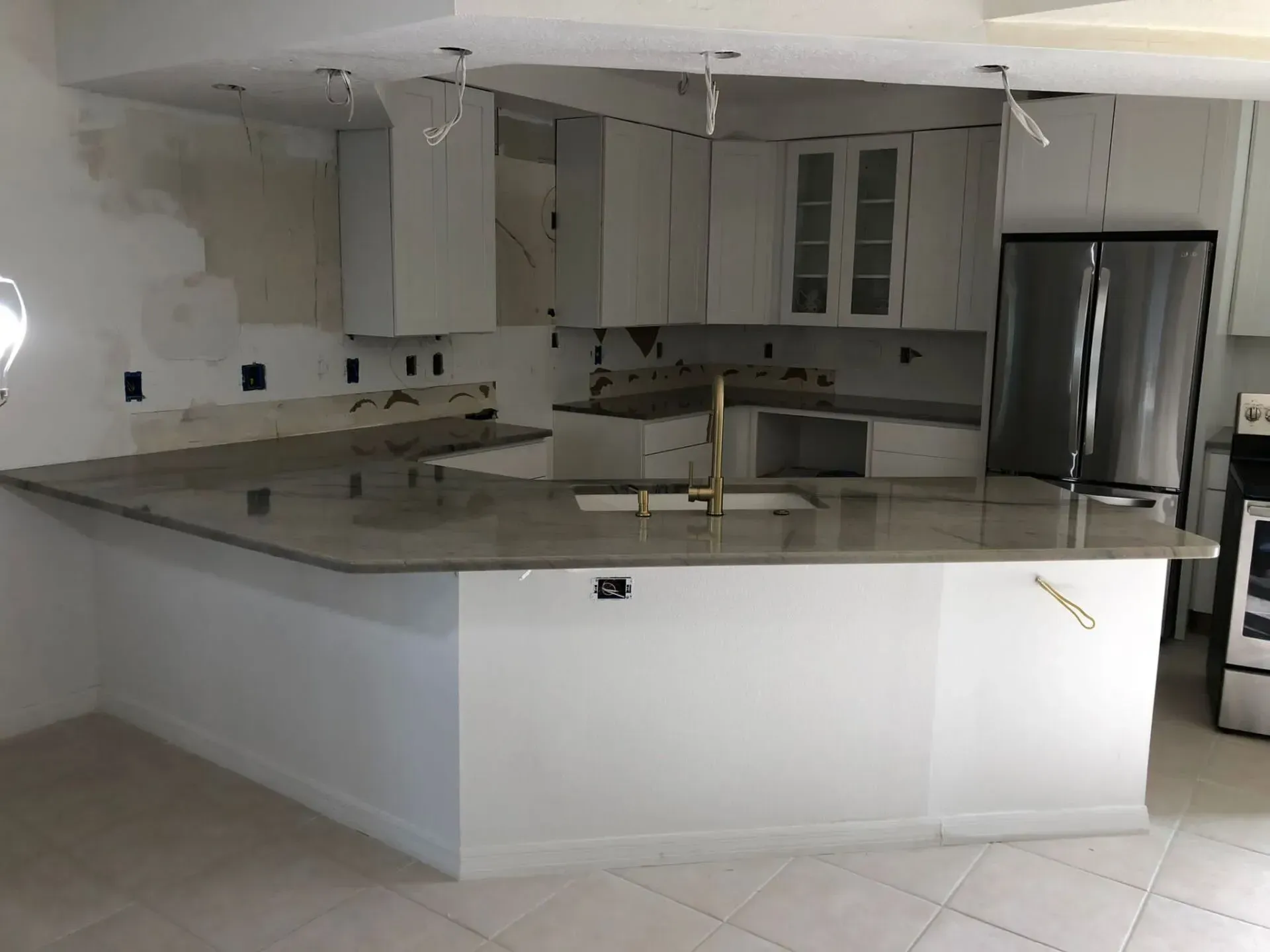 Modern kitchen with white cabinets, granite island, and stainless-steel refrigerator