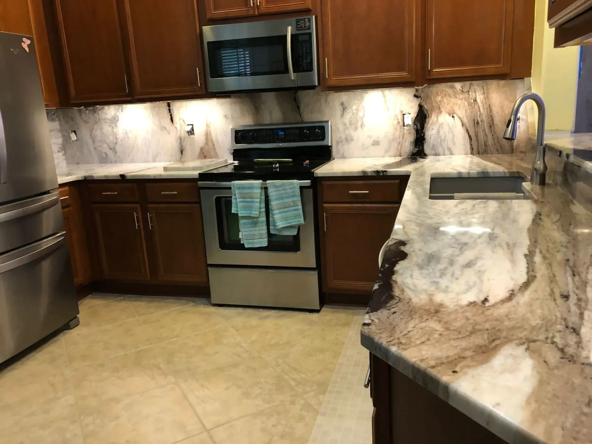 Modern kitchen with stainless steel appliances, dark wood cabinets, and a granite countertop island.