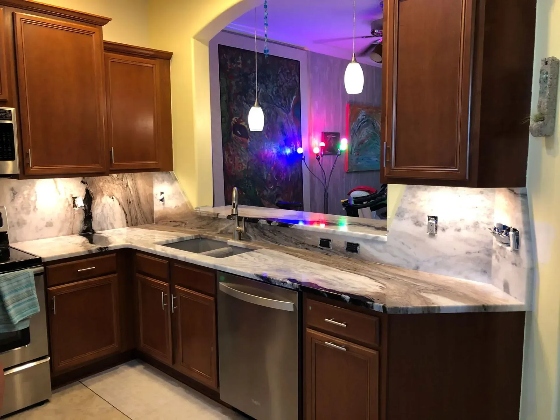 Modern kitchen with dark wood cabinets, granite countertops, stainless appliances, and a pass-through to a lit room