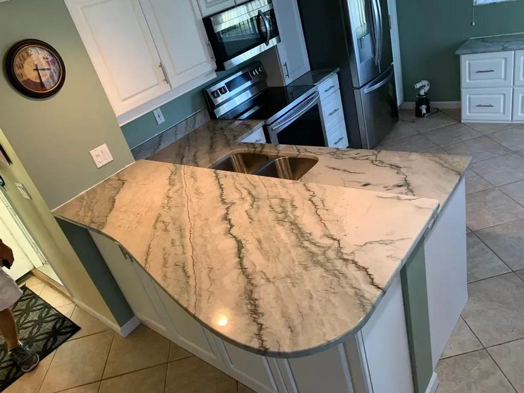 Kitchen with large white marble island, stainless appliances, and light gray tiled floor.