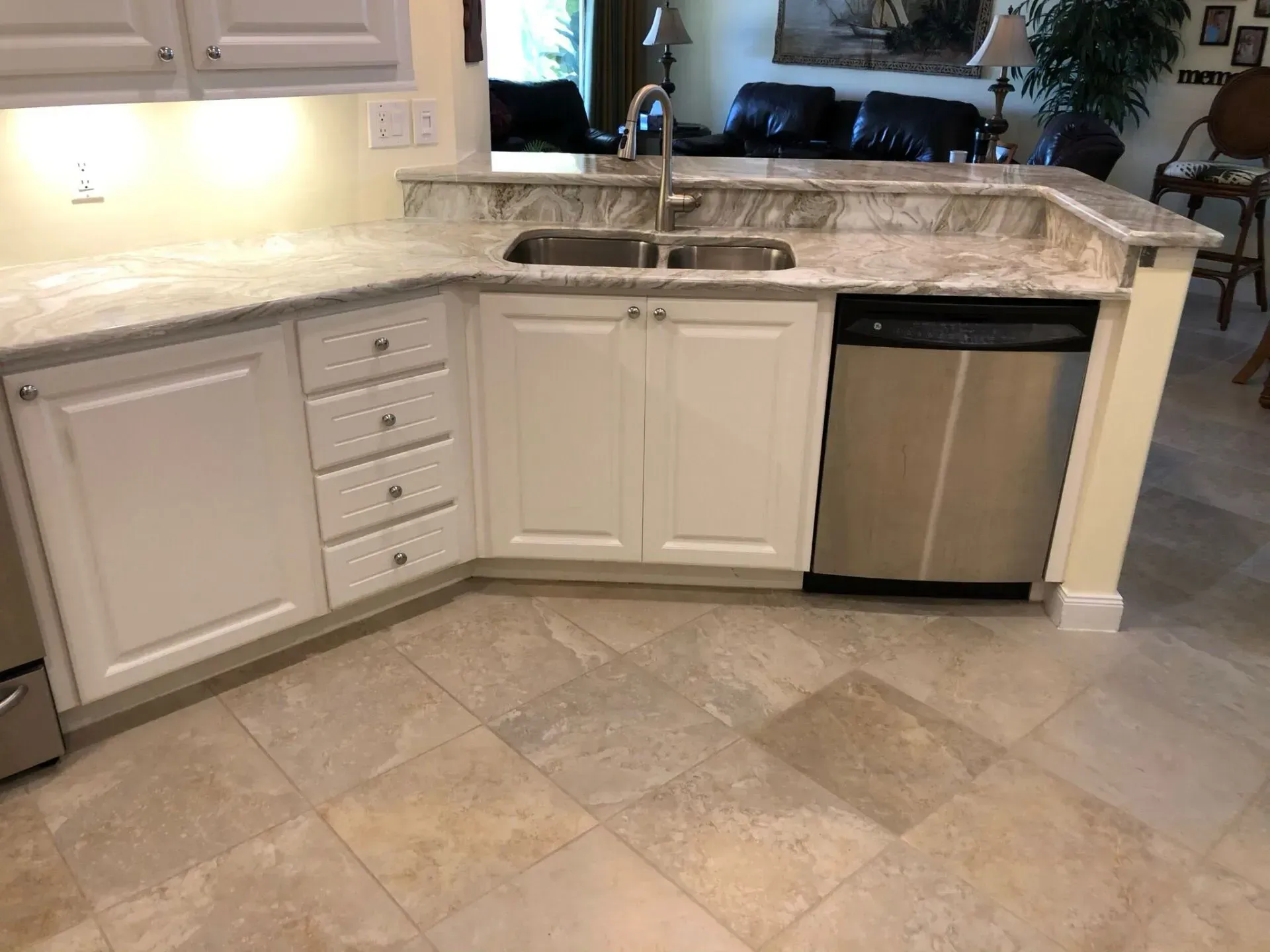 Modern kitchen with white cabinets, marble countertop, sink, dishwasher, and tiled floor