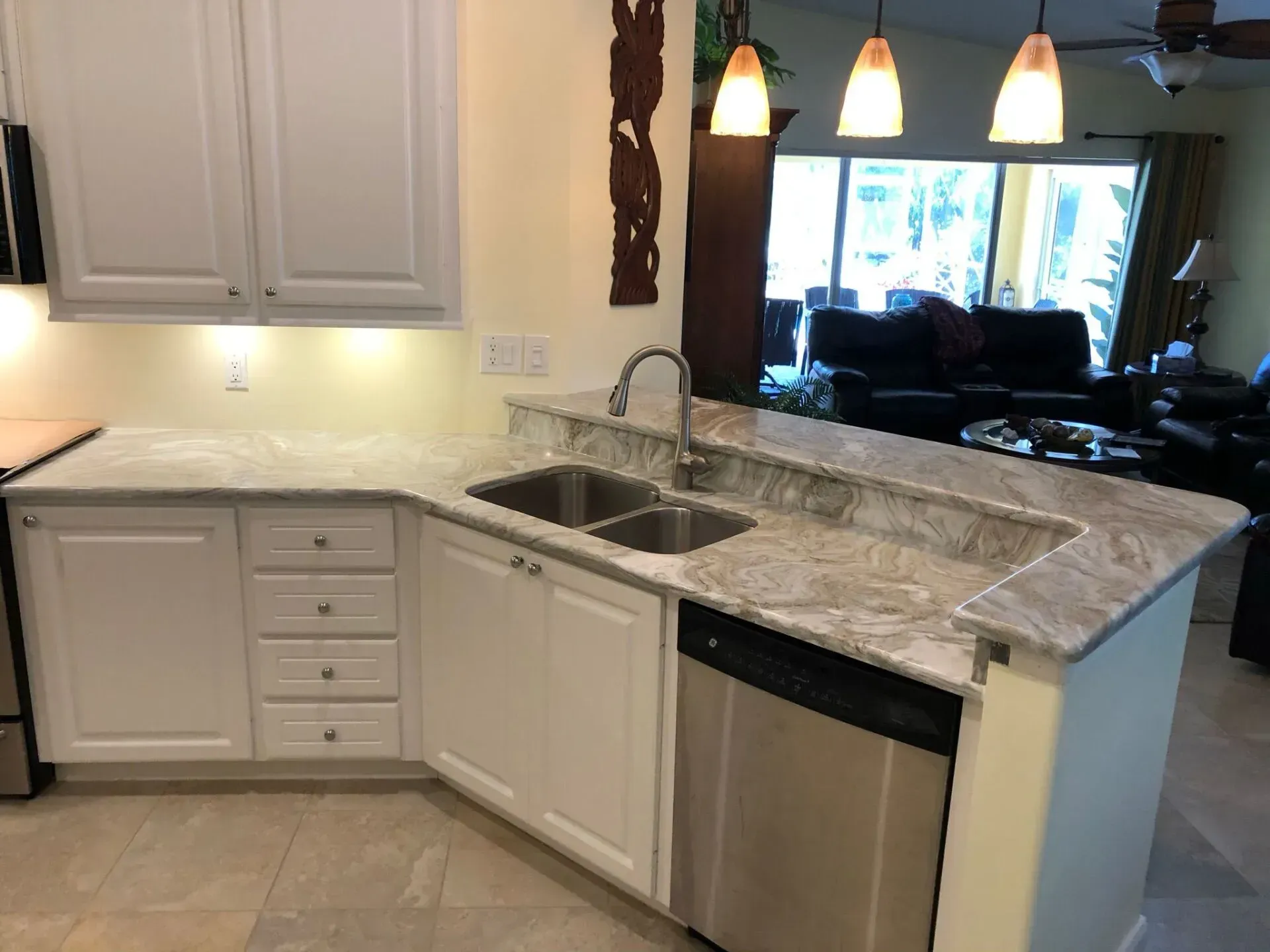 Modern kitchen with white cabinets, granite countertops, sink, and pendant lights overlooking a living room