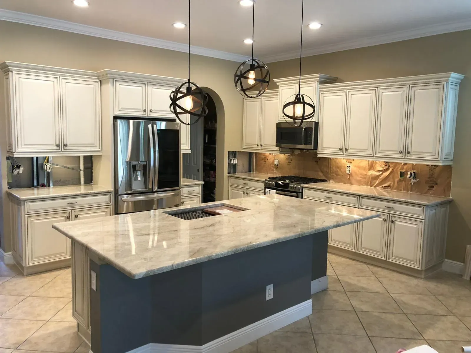 Modern kitchen with white cabinets, stainless steel appliances, large island, and pendant lights