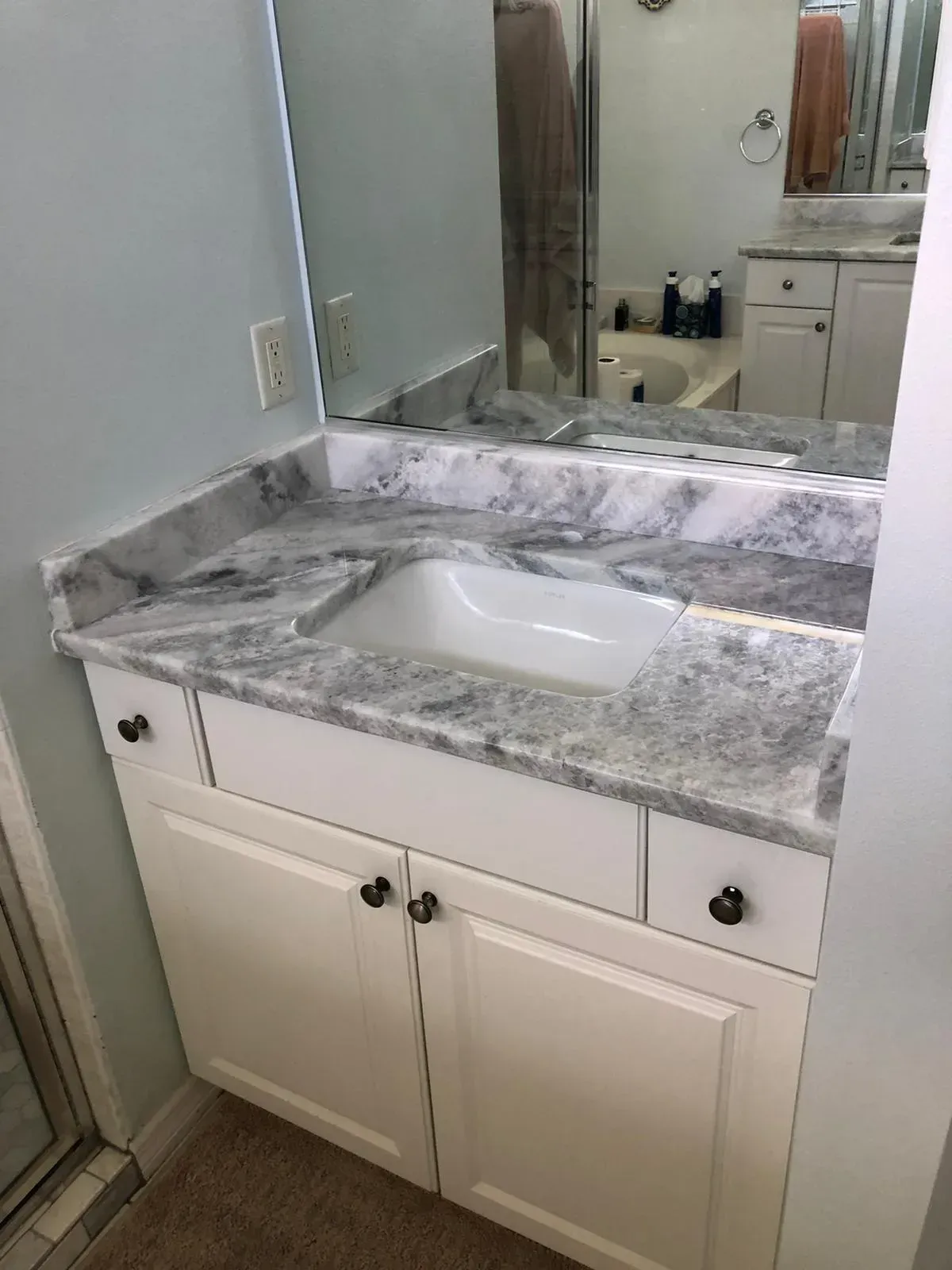 Bathroom vanity with granite countertop, white sink, and large wall mirror.