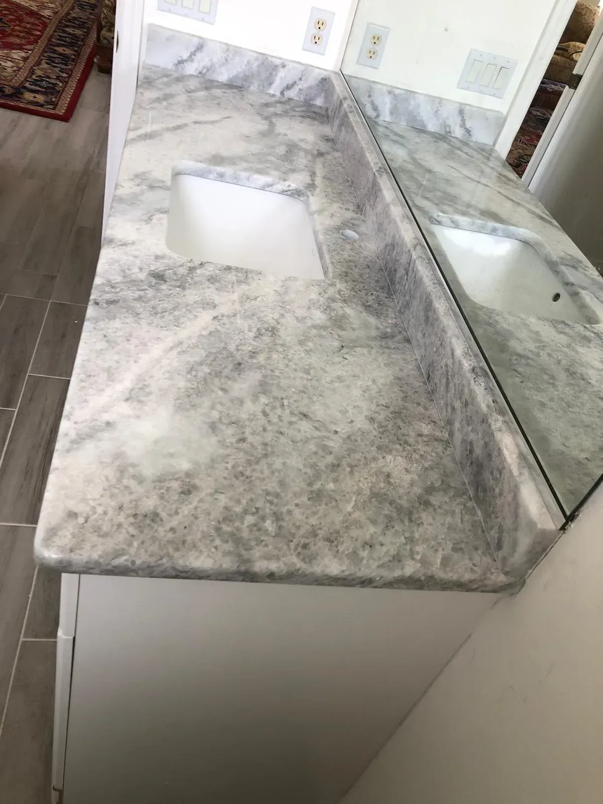 Marble bathroom vanity with rectangular sink and large mirror, shown from above.