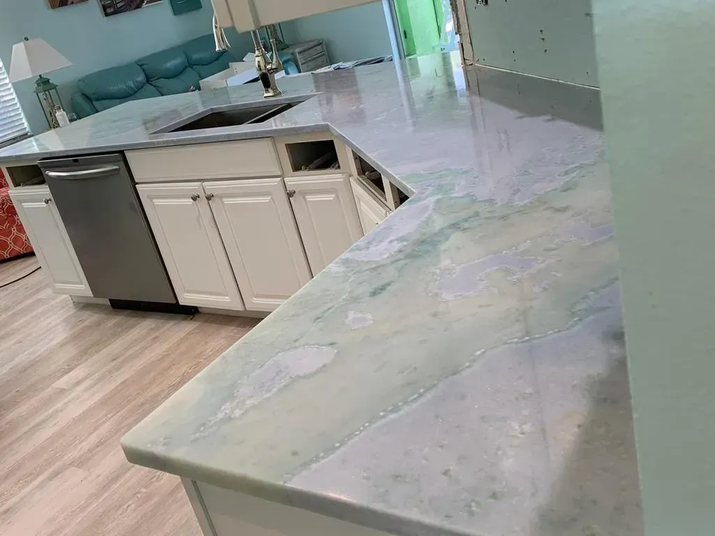 Modern kitchen with marble island countertop, white cabinets, and stainless steel dishwasher