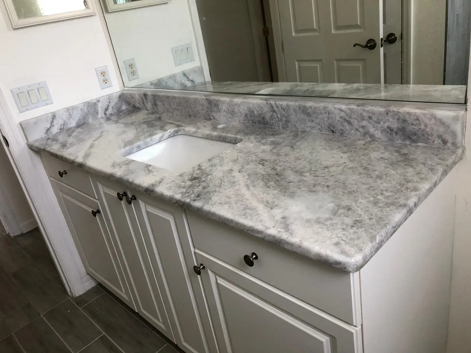 Marble-look bathroom vanity with undermount sink, double cabinets, and large mirror, in a light gray room