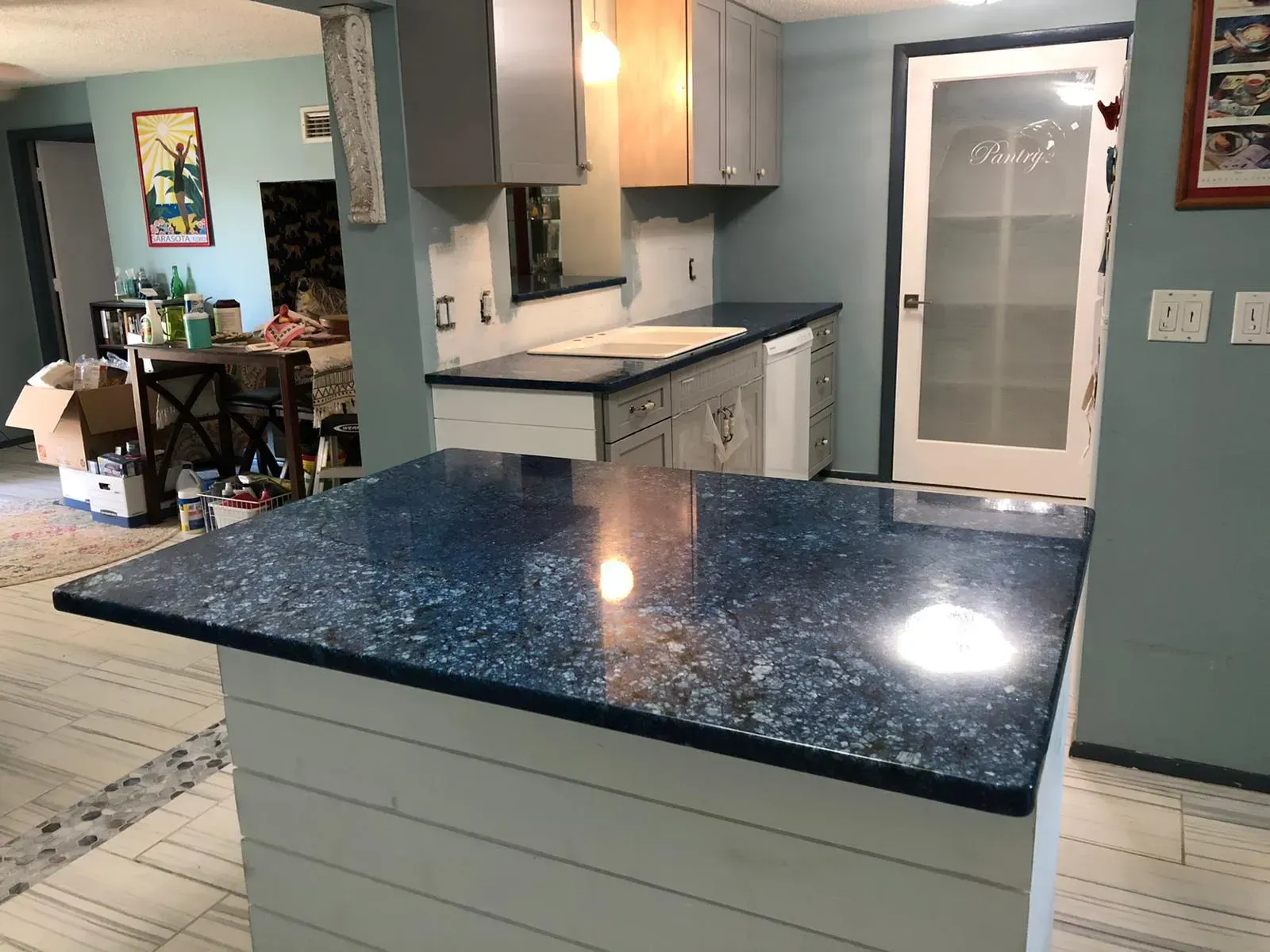 Modern kitchen with blue-speckled island, light cabinets, and a glass door at the back