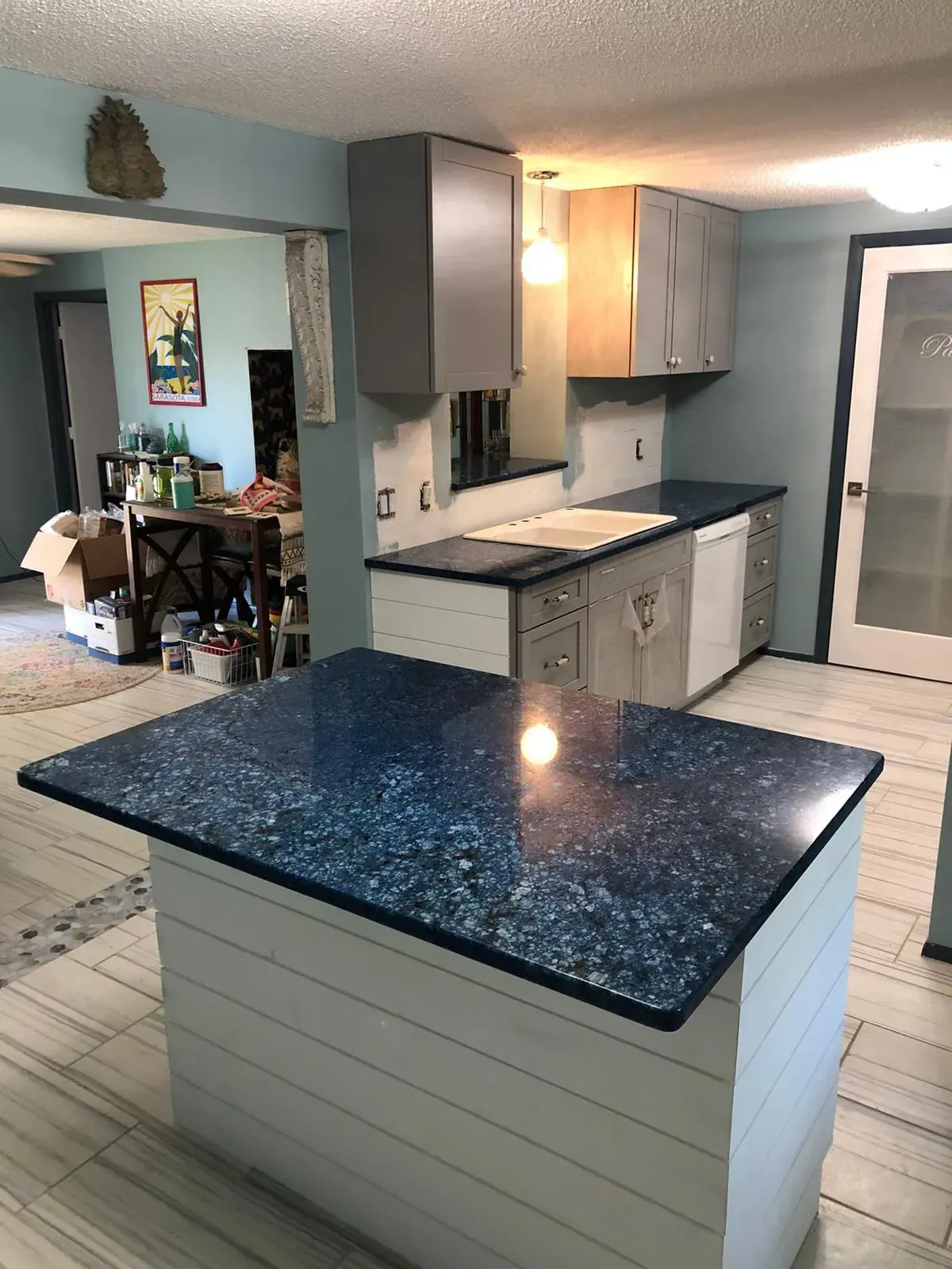 Kitchen with blue granite island, light cabinets, and a dining area in the background.