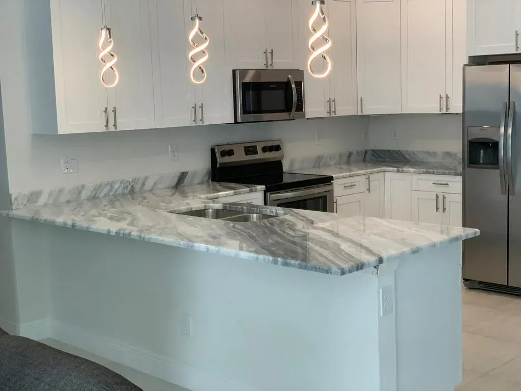Bright modern kitchen with white cabinets, stainless appliances, and a gray marble island countertop