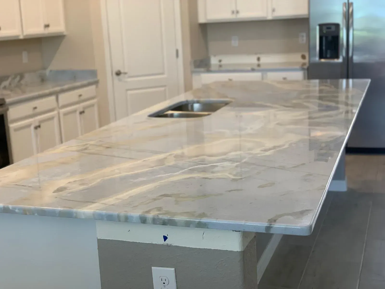 Kitchen with white marble island countertop and built-in sink, in a bright modern interior