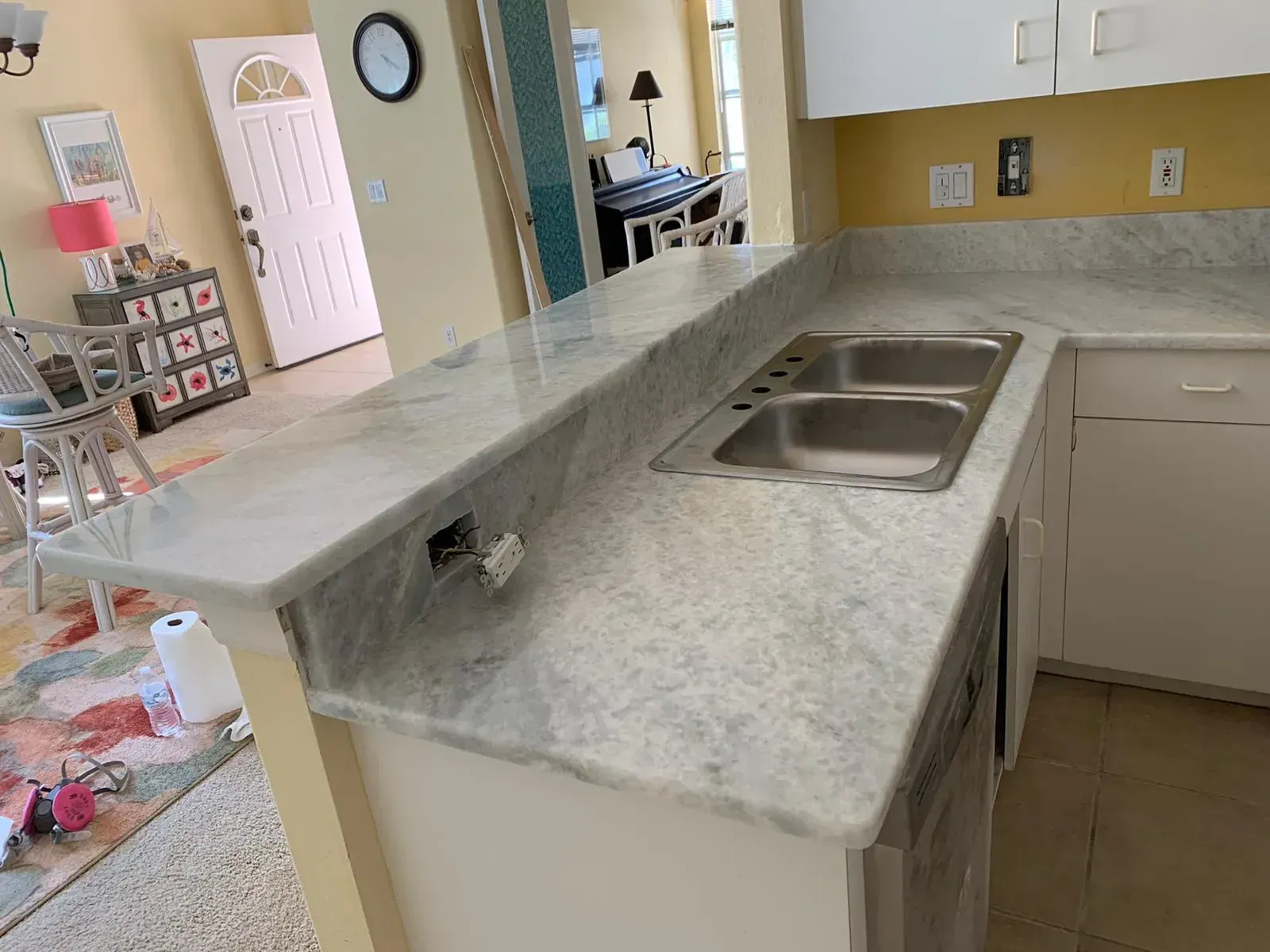 Kitchen island with double sink and gray marble countertop in a bright home interior