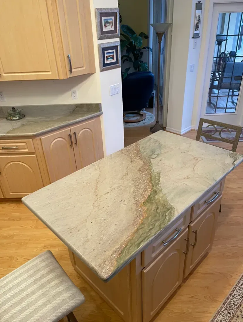 Kitchen island with a beige and green stone countertop in a bright home kitchen.