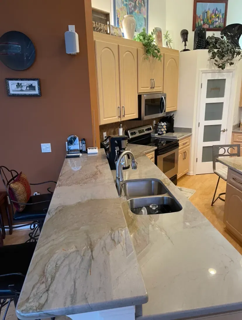 Modern kitchen with marble island, sink, wood cabinets, and stainless steel appliances