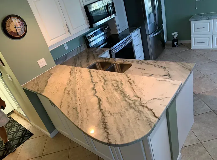 Modern kitchen with marble island, stainless appliances, and light tile flooring