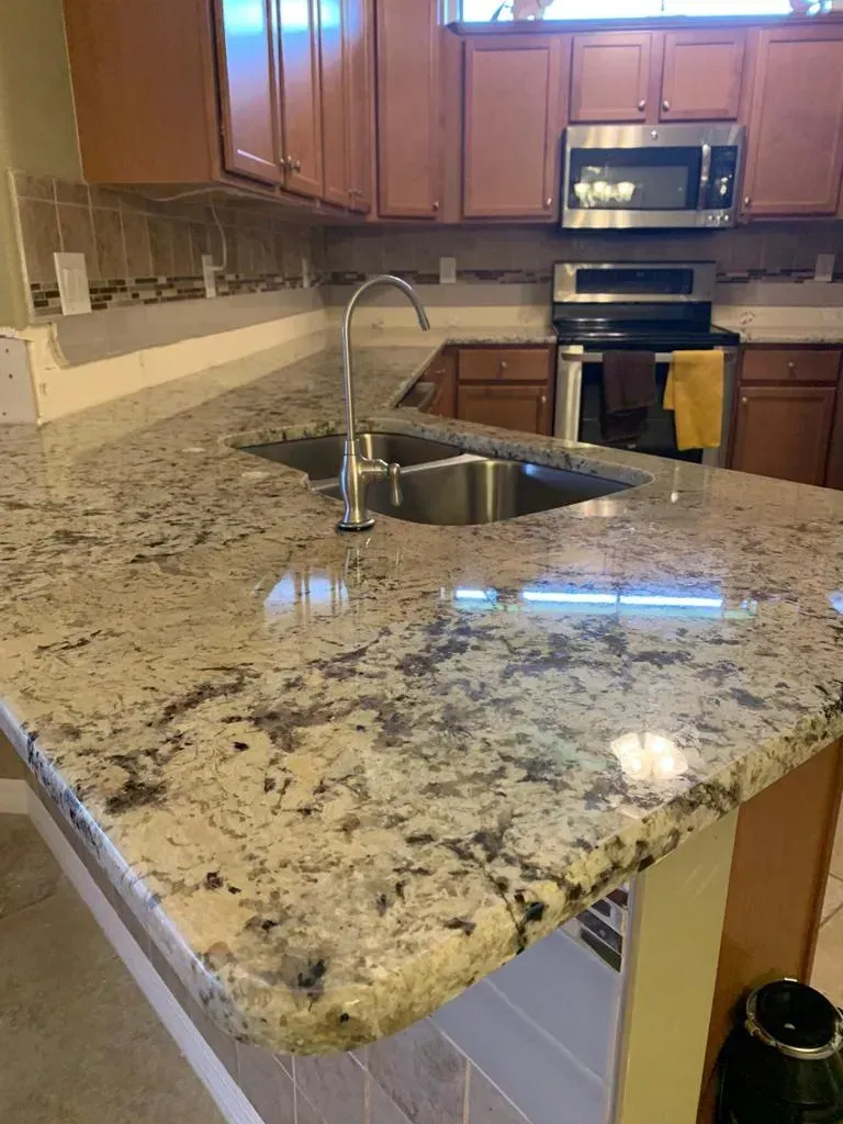 Kitchen with granite countertop, sink, and wooden cabinets, viewed from the counter edge