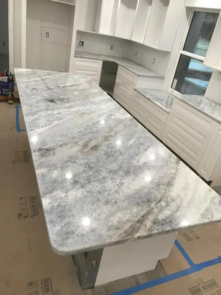 Large gray-and-white stone kitchen island countertop in a bright unfinished kitchen