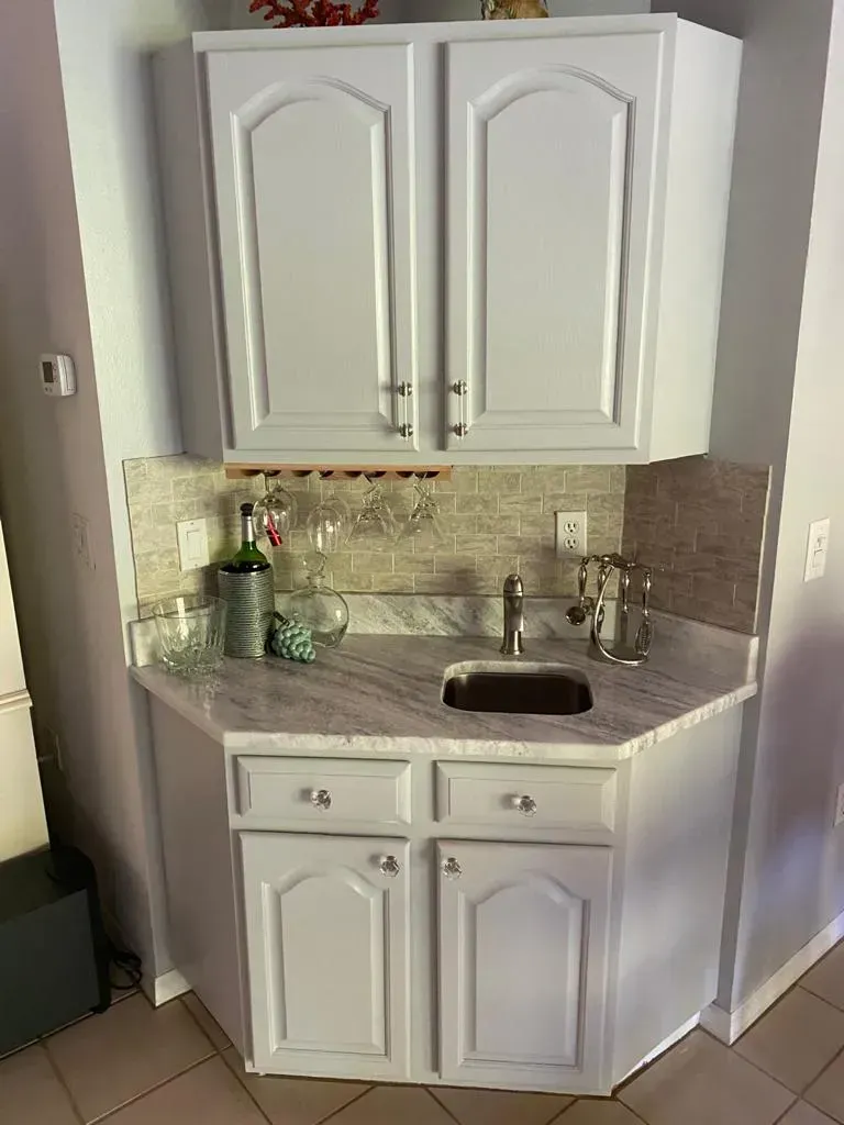 White bathroom vanity with sink, mirror cabinet, and tiled backsplash in a small corner nook