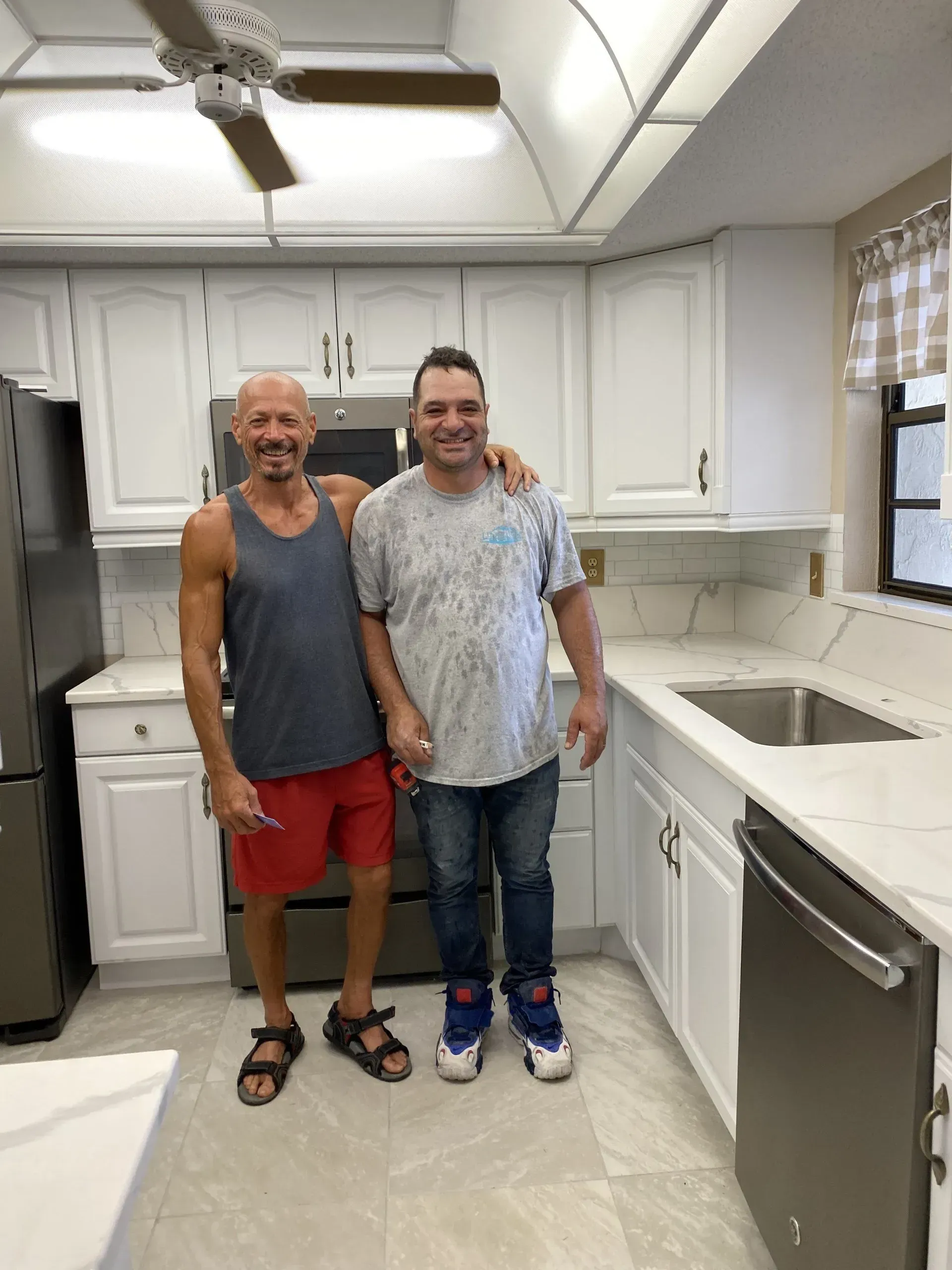 Two people standing together in a bright kitchen, smiling and posing.