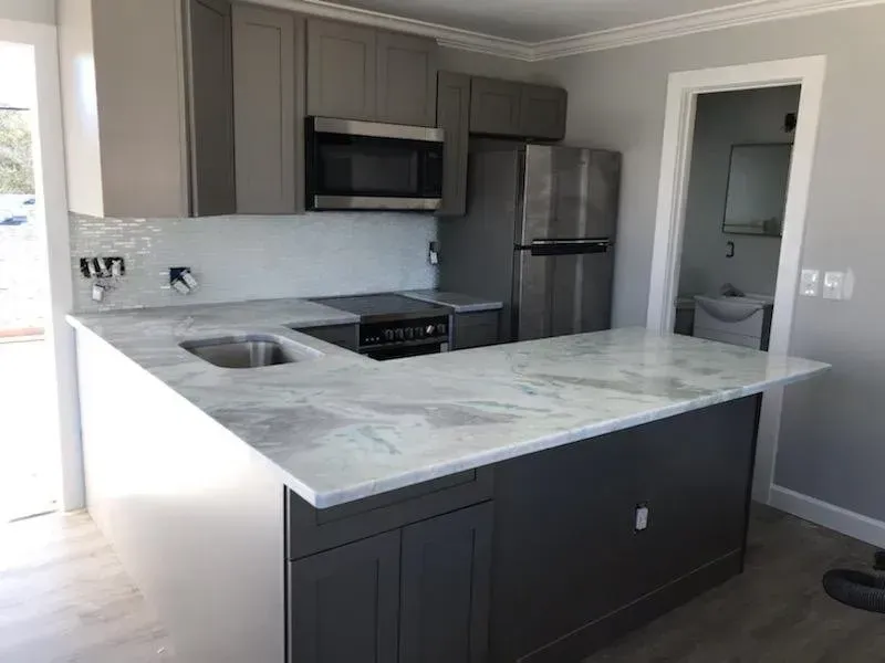 Modern kitchen with dark cabinets, marble island, stainless-steel appliances, and gray walls