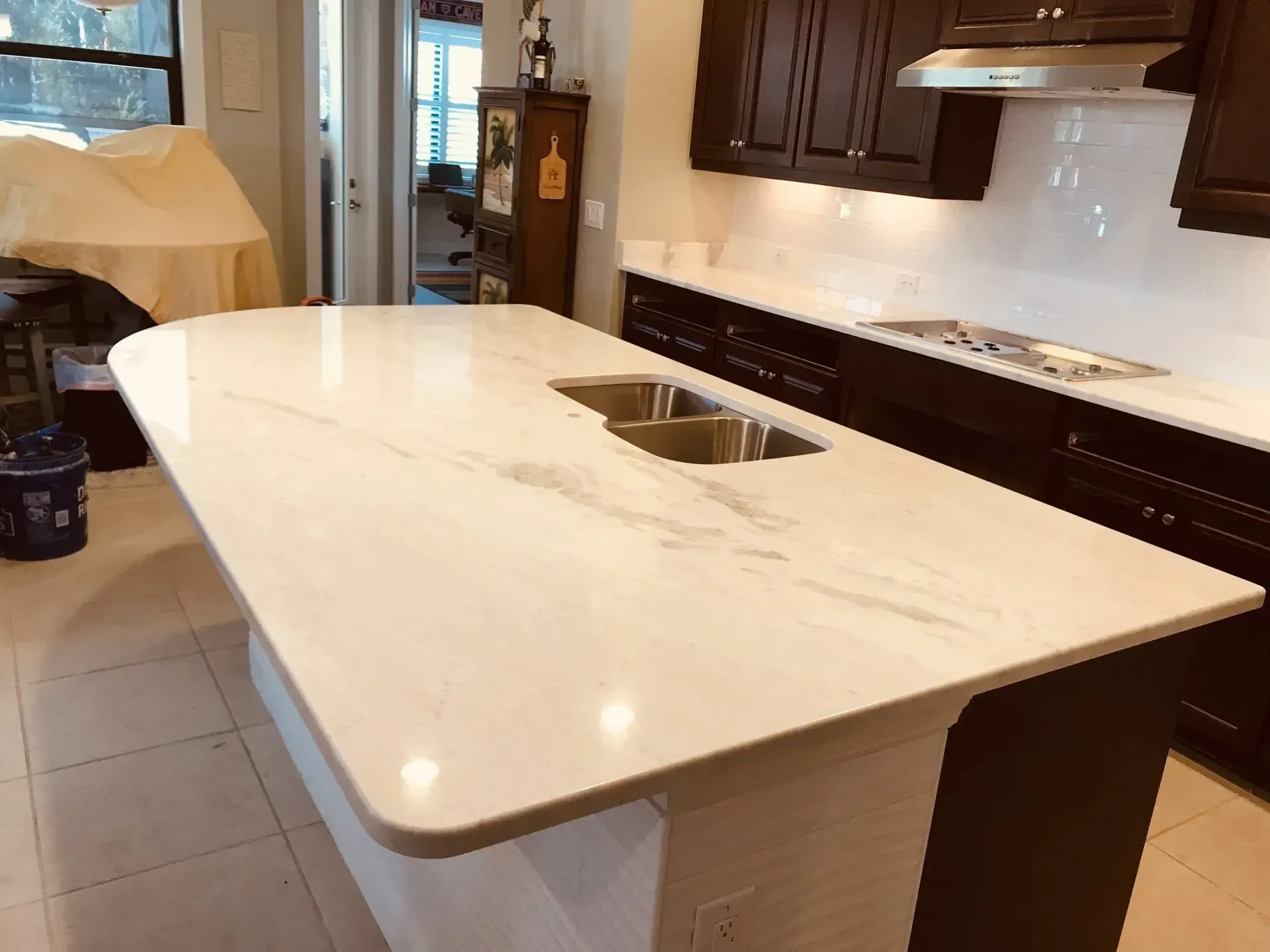 Modern kitchen with a large white island, built-in sink, and dark wood cabinets