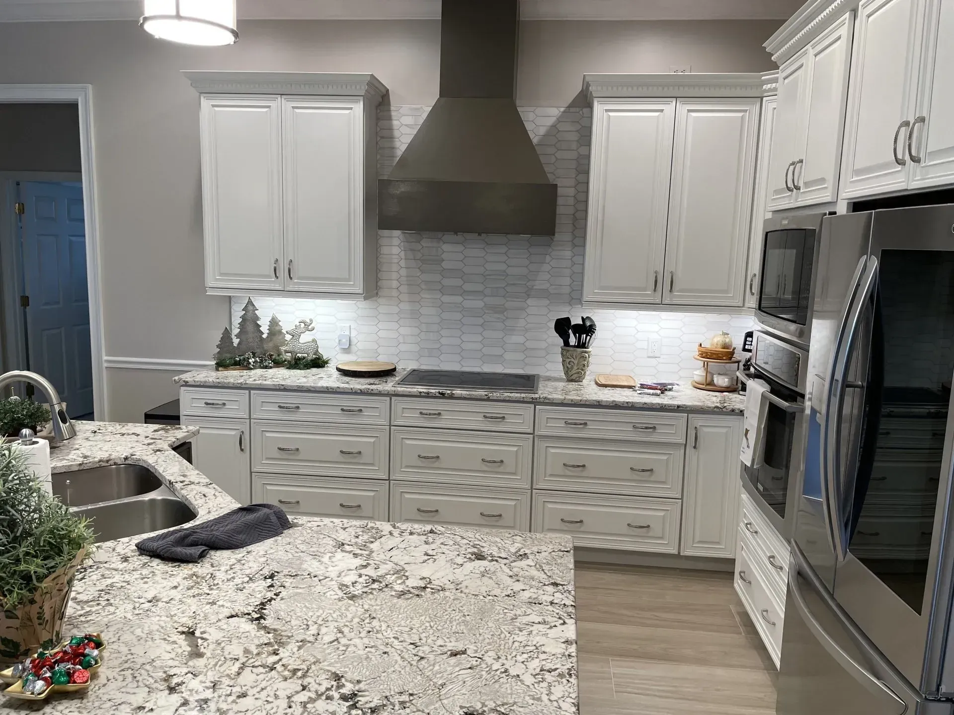 Modern kitchen with white cabinets, granite island, stainless appliances, and gray range hood