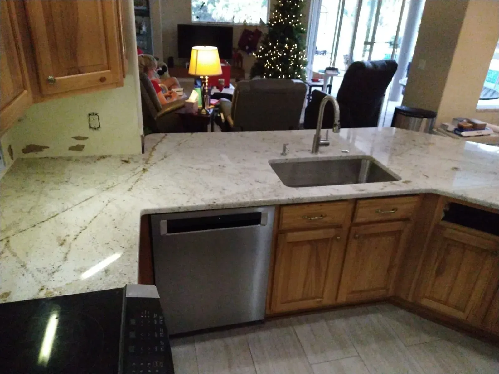 Kitchen with marble countertops, wooden cabinets, sink, and stainless dishwasher in a home interior.