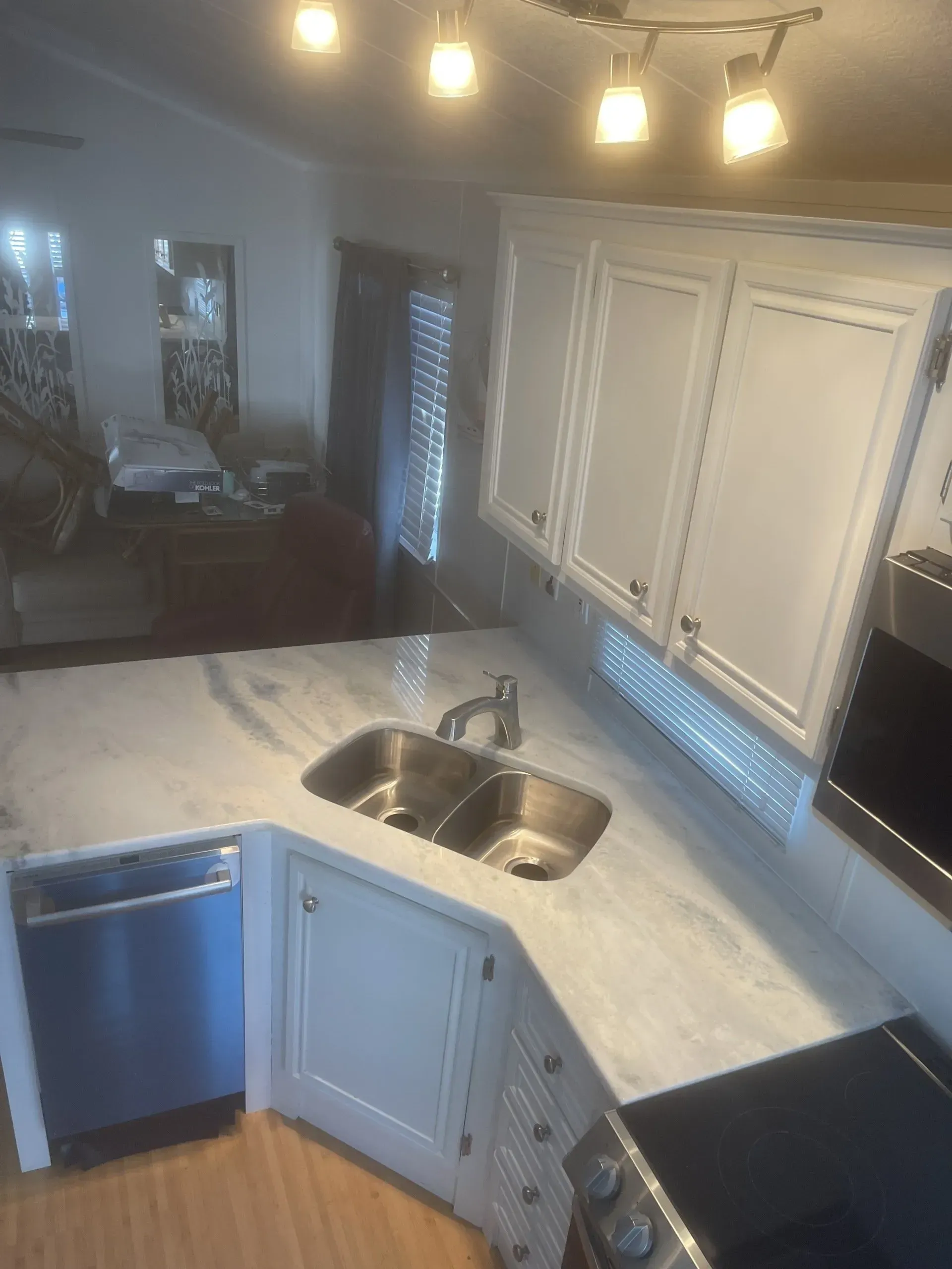 Modern kitchen with white cabinets, marble countertop, stainless sink, and blue drawers under pendant lights