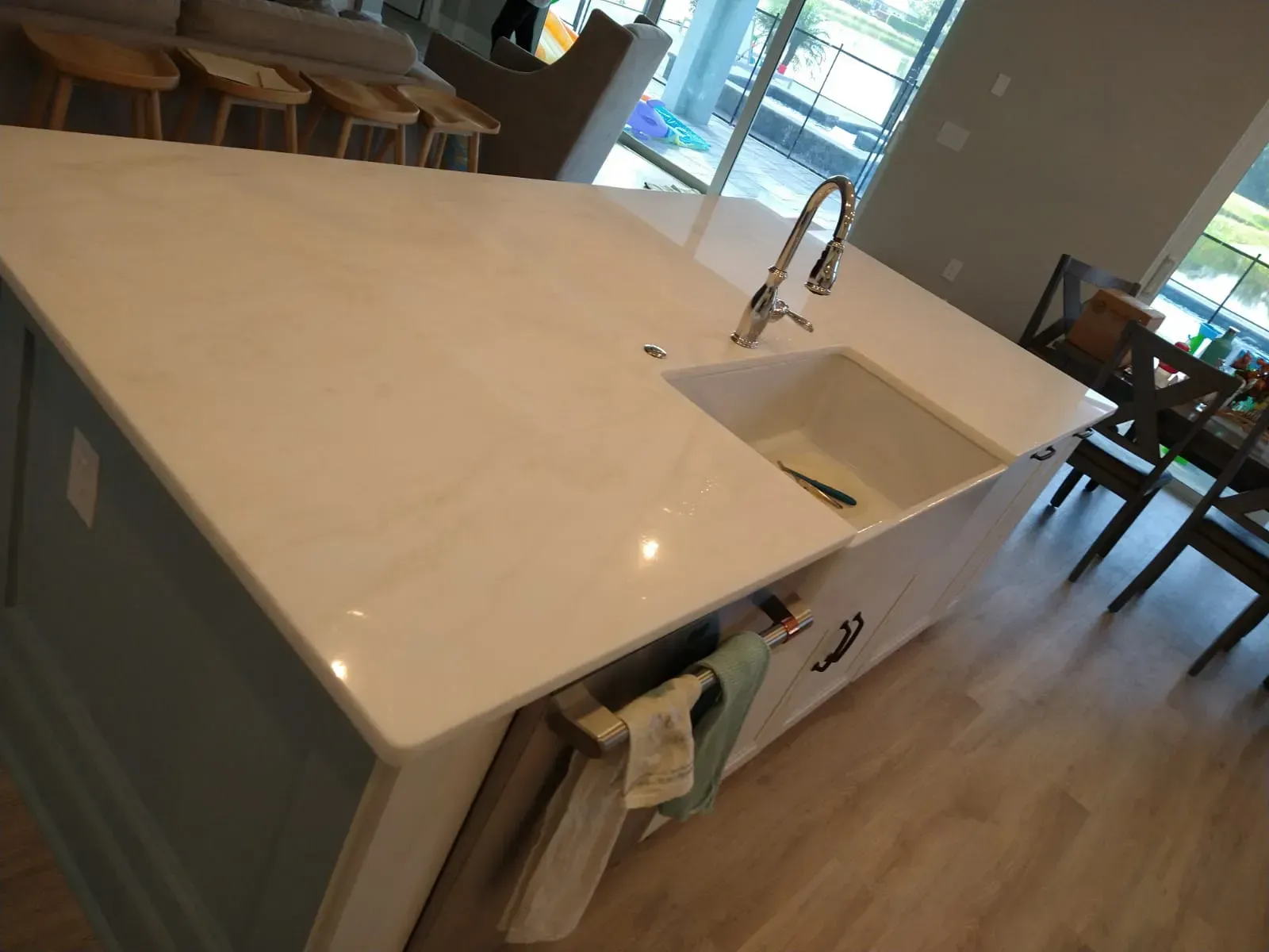 Bright kitchen island with white countertop, sink, faucet, and wooden floor in a modern room.